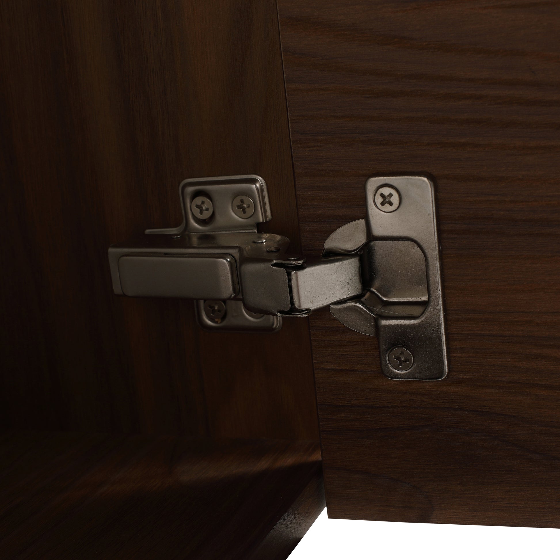 Closeup of brushed nickel cabinet hinge attached to dark walnut wood door