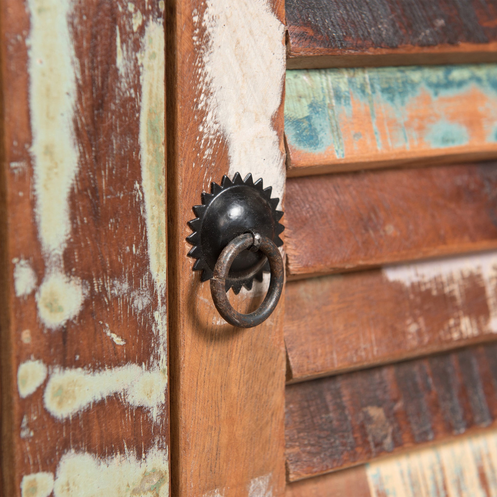Closeup of distressed reclaimed wood cabinet with black starburst knob and ring pull