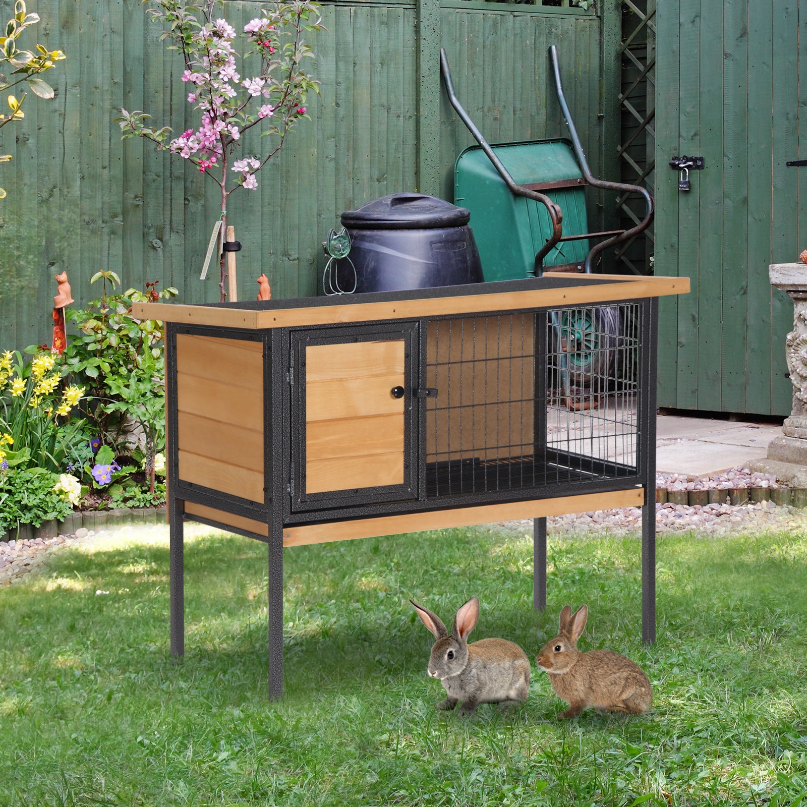 Two rabbits near a wooden and wire outdoor pet hutch with a garden backdrop
