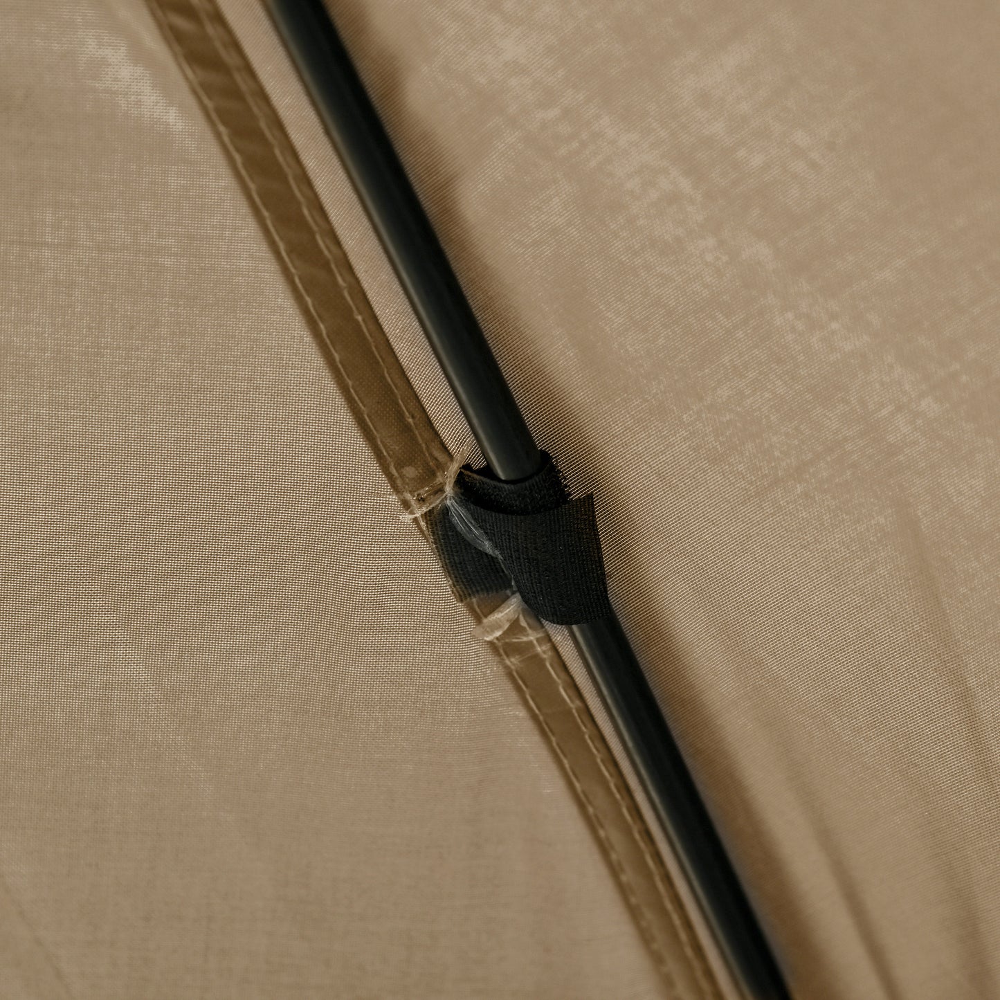 Closeup of tan nylon tent fabric with black pole securing strap