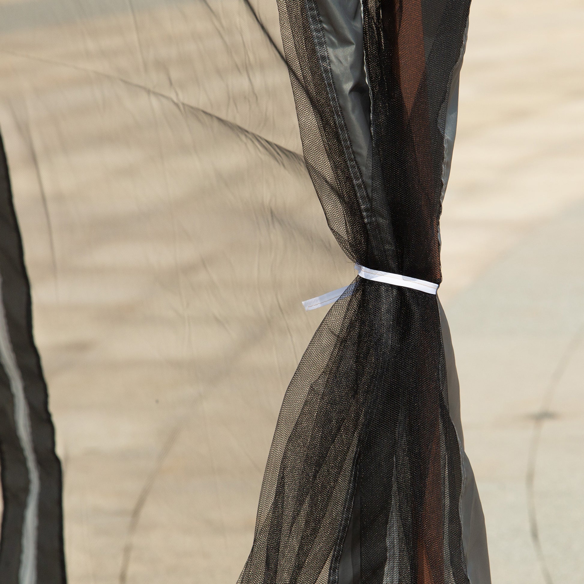 Closeup of black mesh mosquito netting fabric with white tie straps on a neutral background