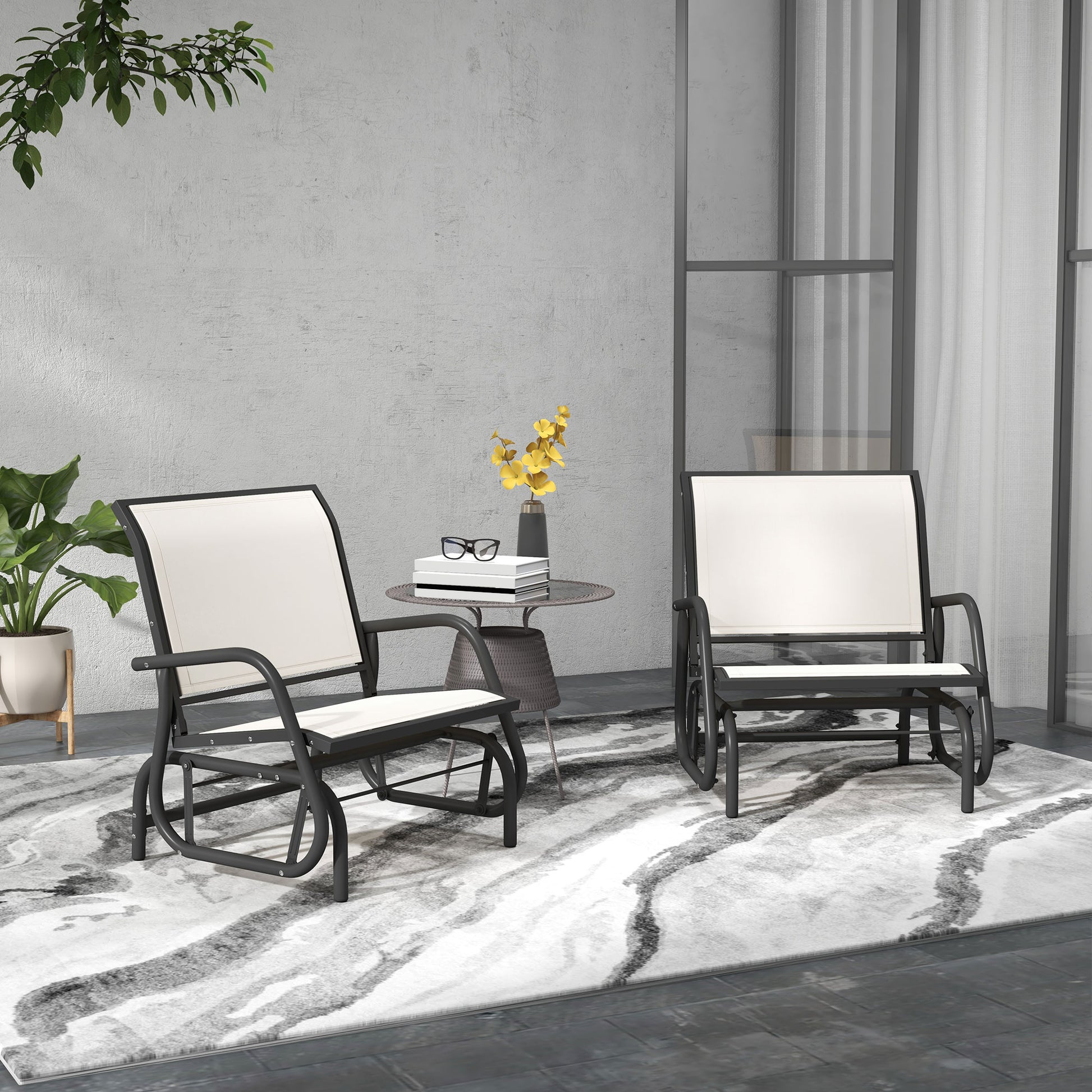 Two black metal outdoor glider chairs with white cushions on a patterned rug