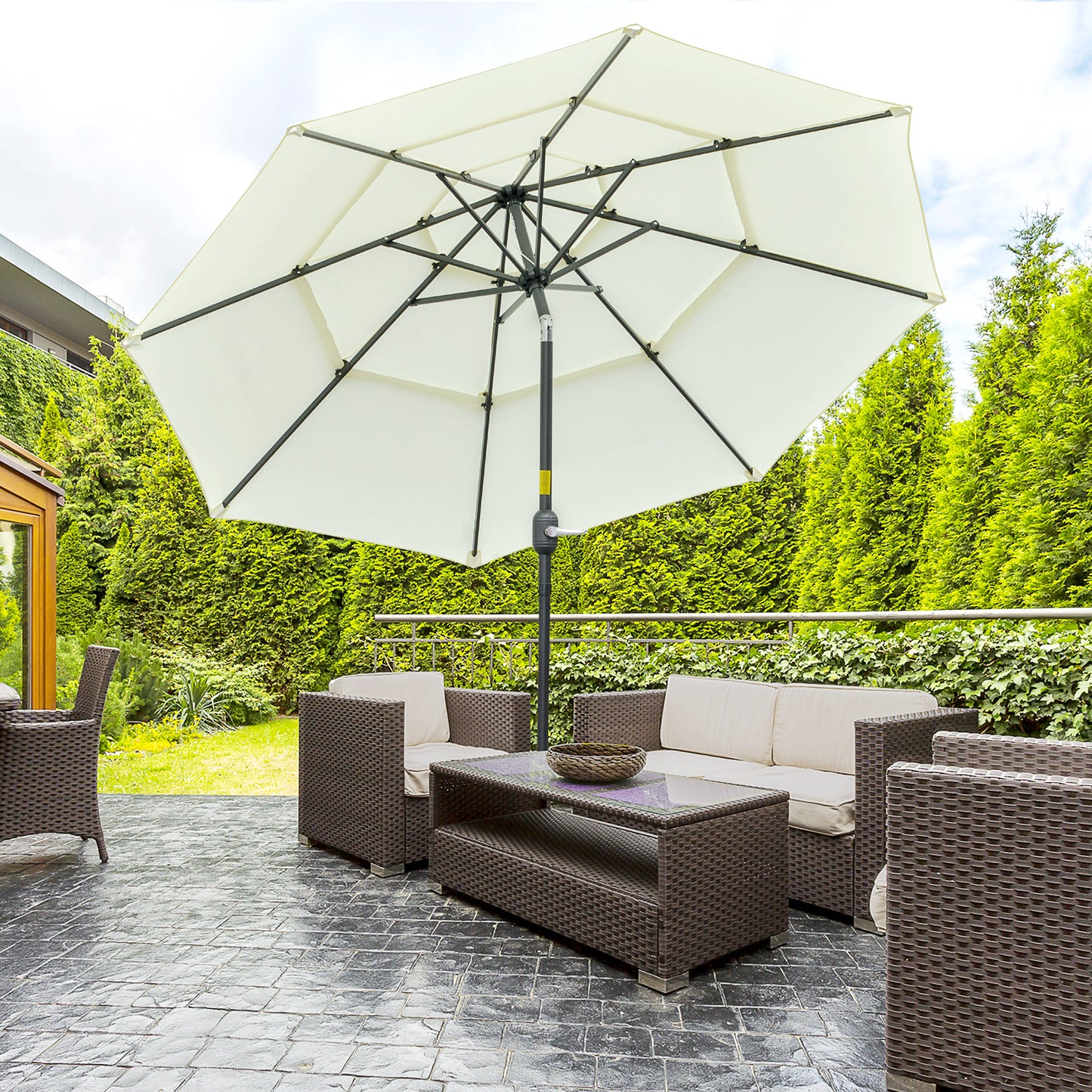 Wicker outdoor furniture set with a large cream umbrella providing shade for a patio