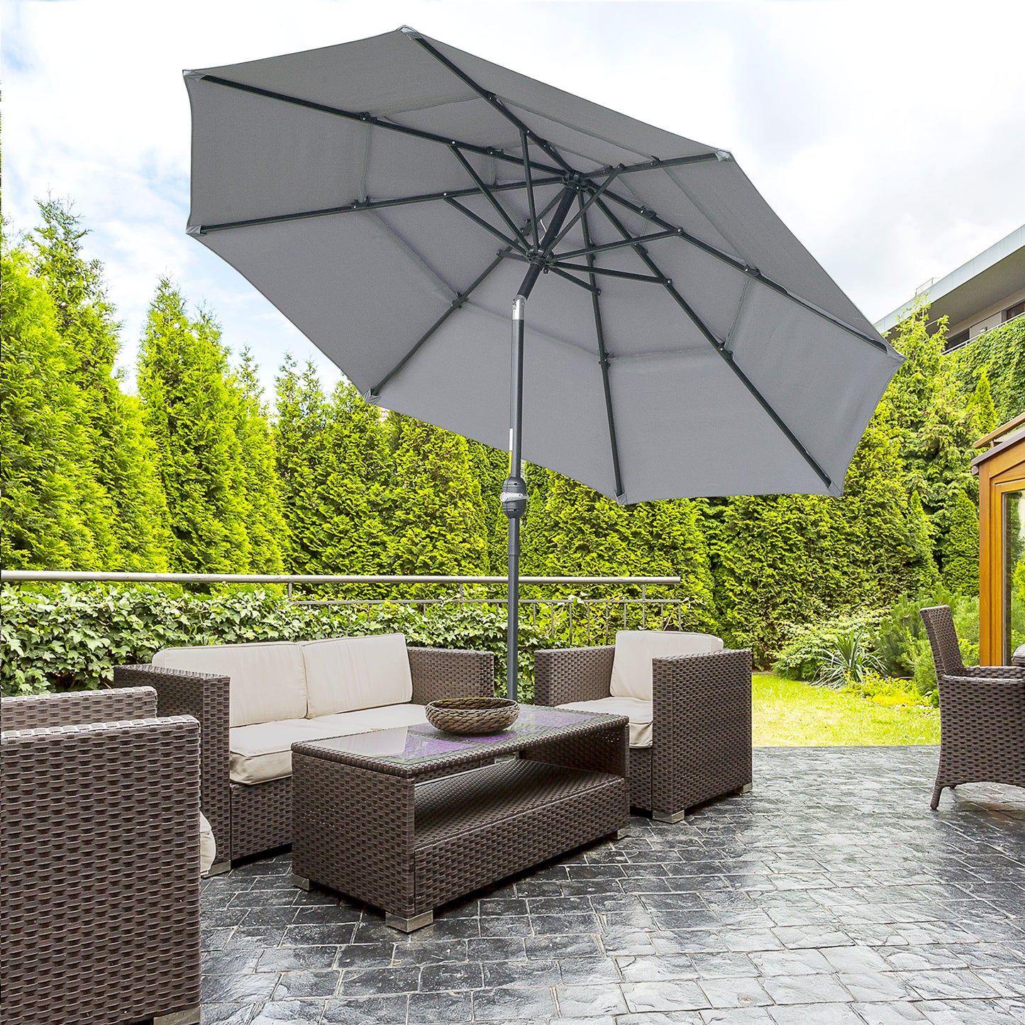 Gray patio umbrella providing shade for a wicker furniture set with beige cushions
