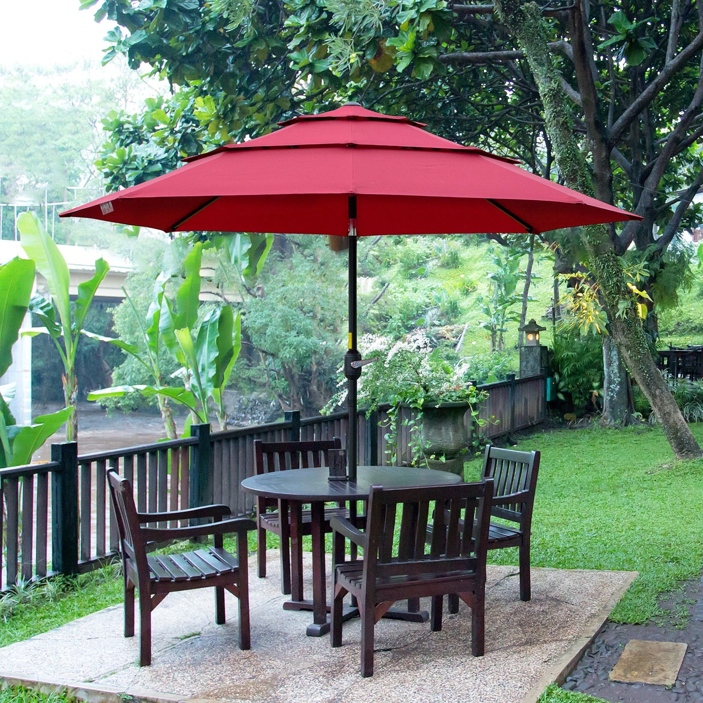 Red patio umbrella with tiered canopy over dark wood outdoor dining set