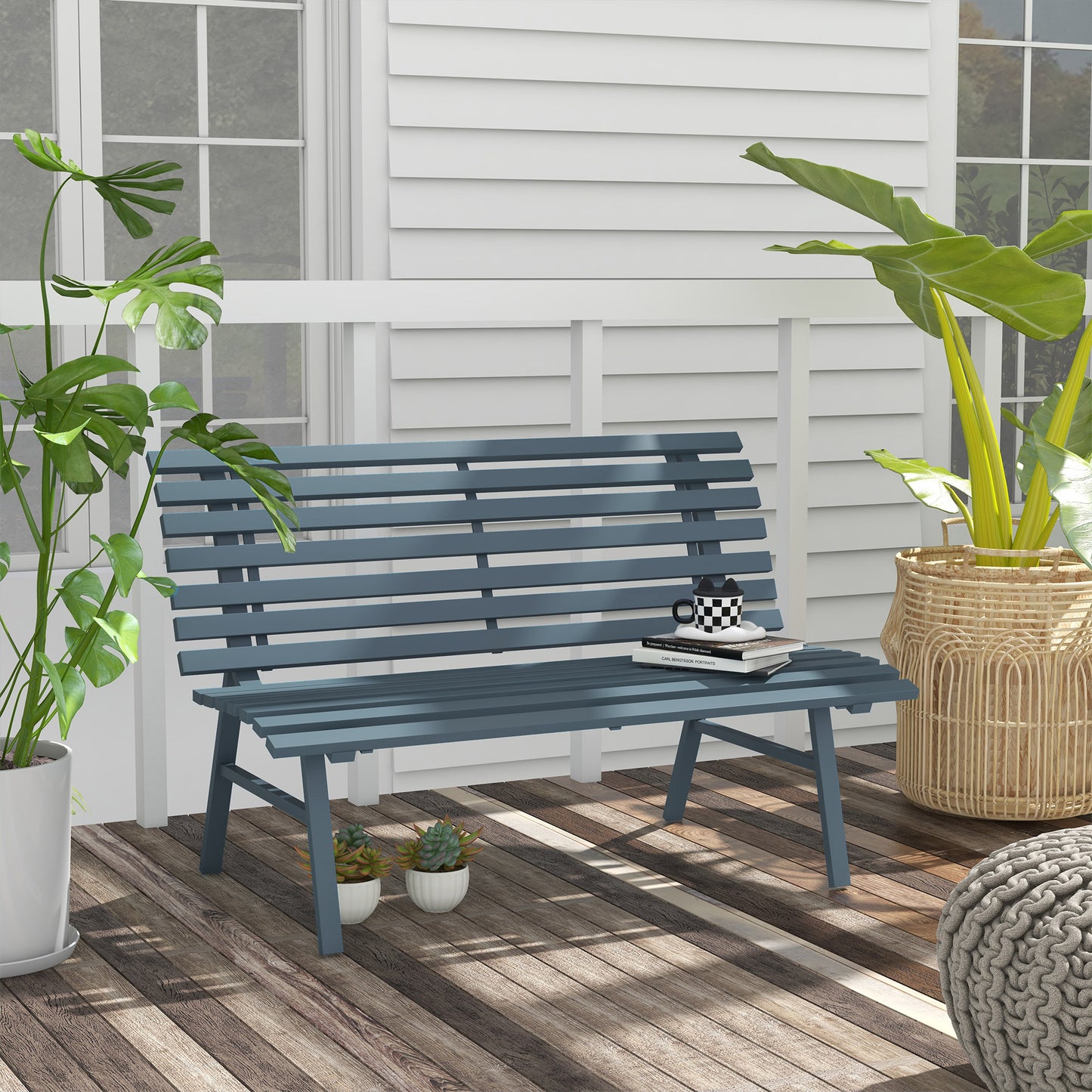 Blue slatted wood outdoor bench with books and mug on seat on a wooden deck