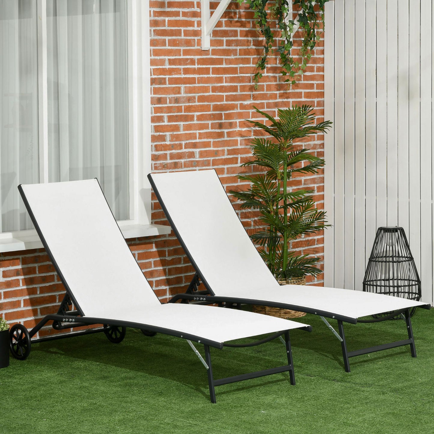 Two white fabric chaise lounges with black metal frames on a green lawn