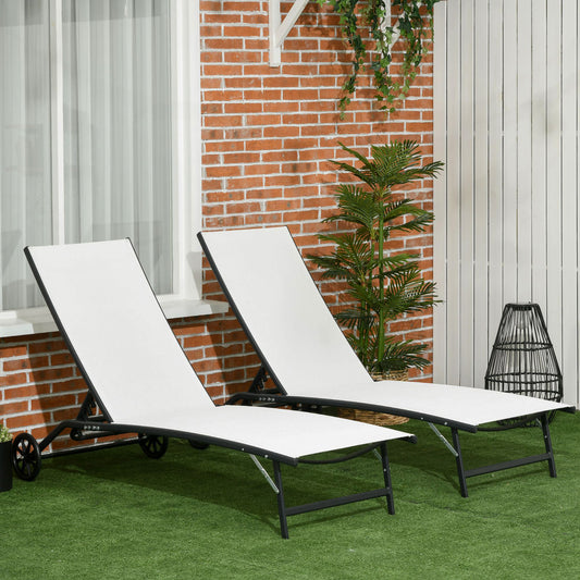 Two white fabric chaise lounges with black metal frames on a green lawn