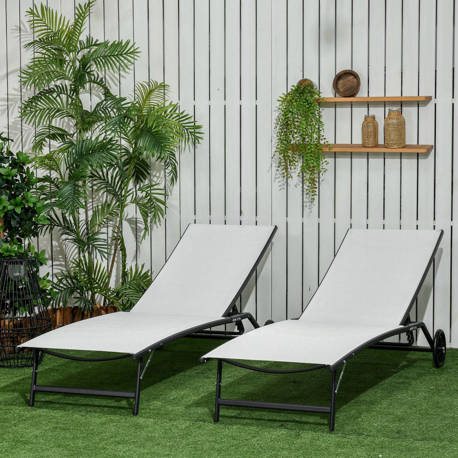 Two grey fabric outdoor lounge chairs with black frames on green grass
