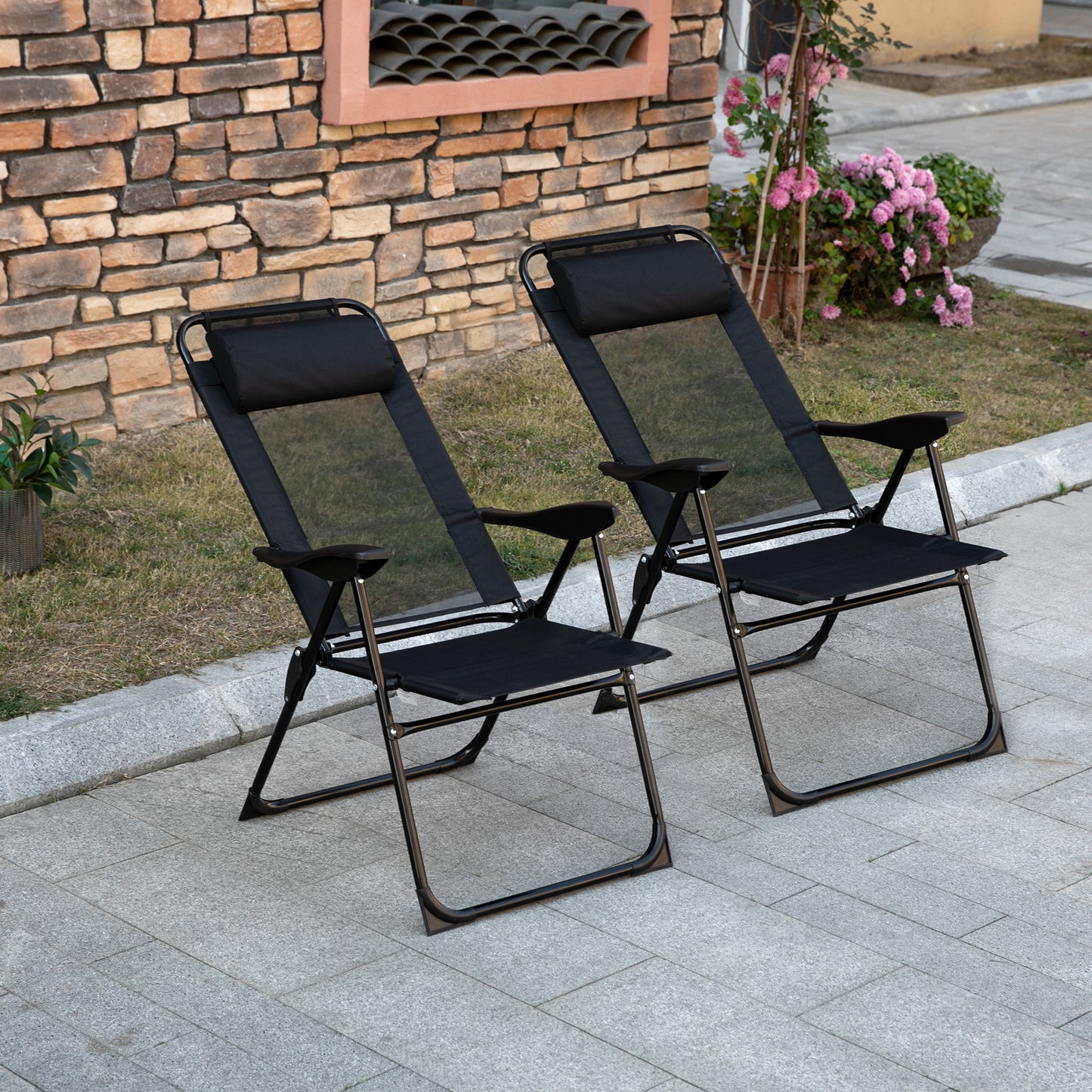 Two black mesh zero gravity chairs with padded headrests on a stone patio