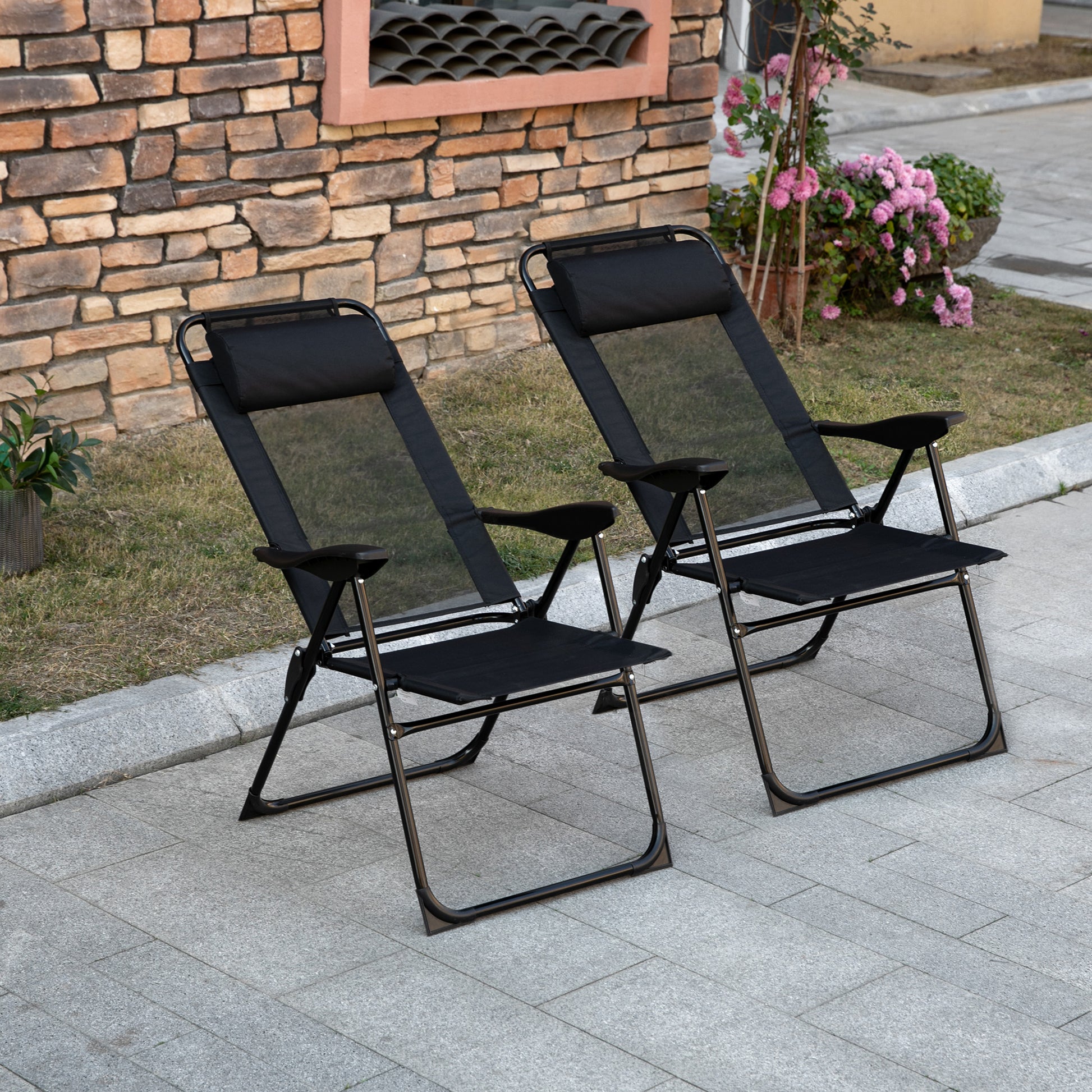 Two black mesh zero gravity chairs with padded headrests on a stone patio
