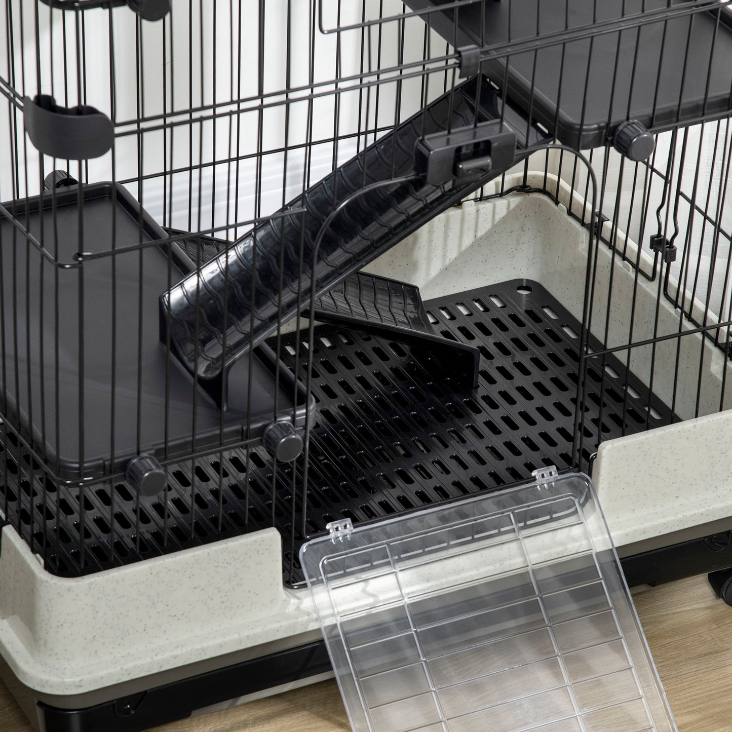 Closeup of a multilevel pet cage with black wire white speckled base and slide for small animals