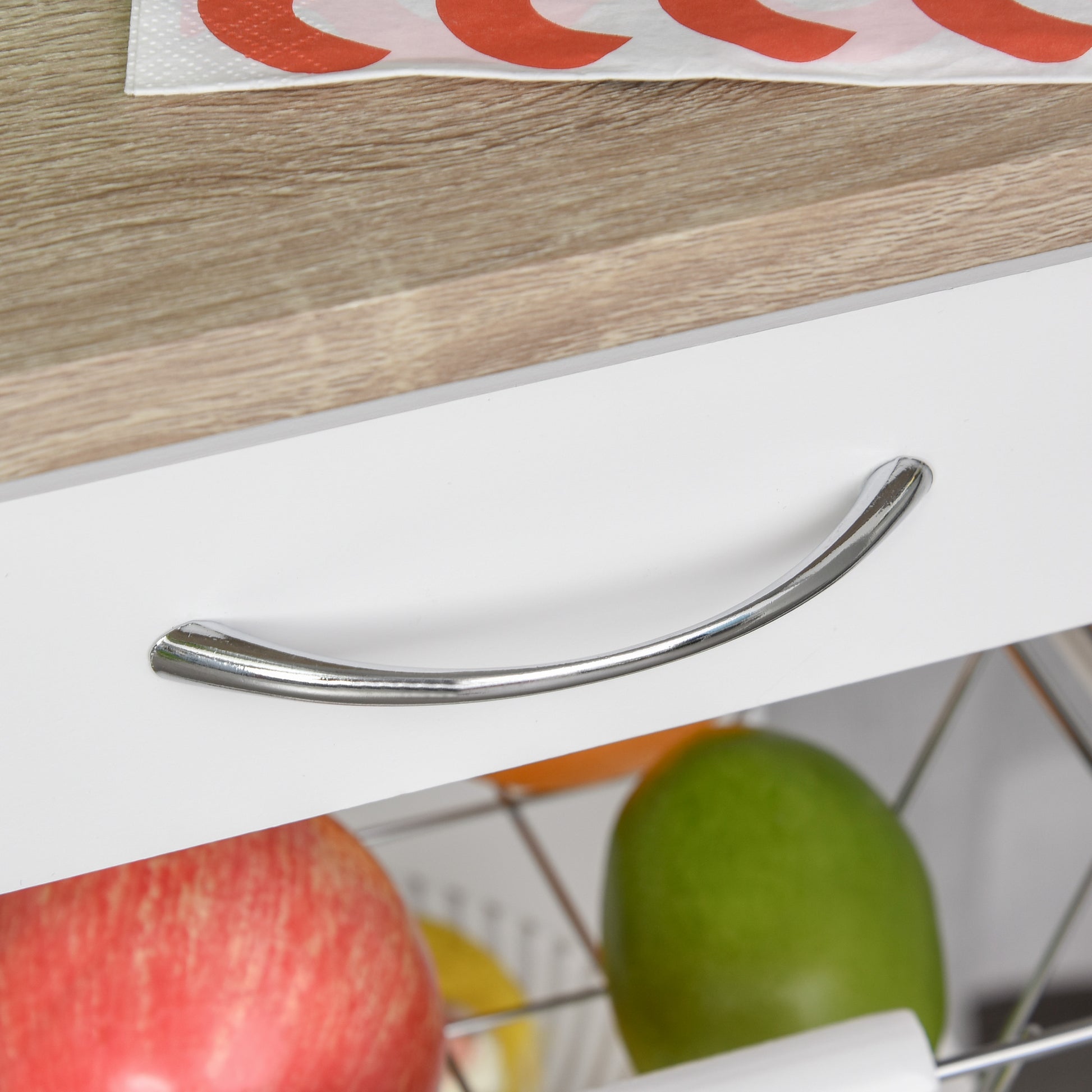 White kitchen cabinet with sleek chrome drawer pull holding fresh red apple