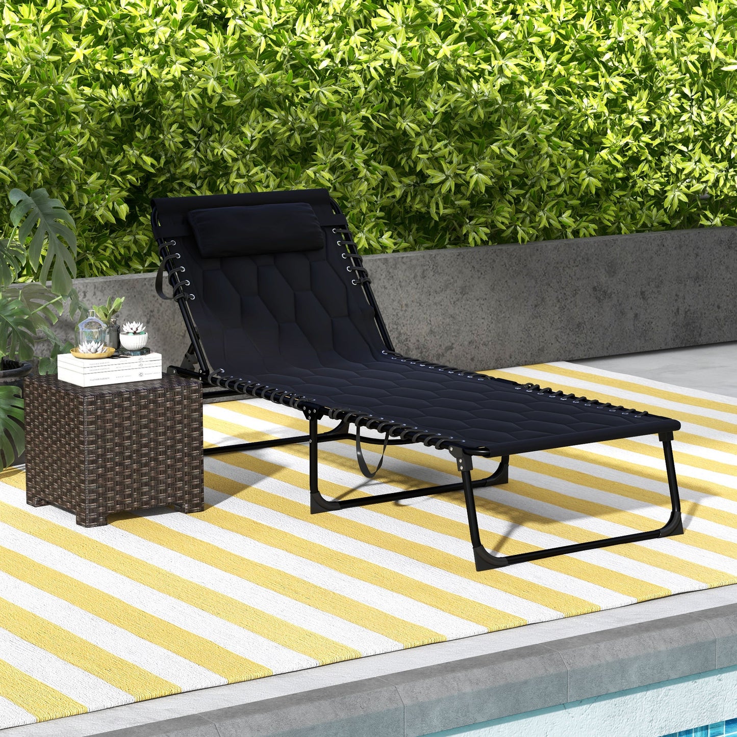 Black outdoor chaise lounge chair with quilted fabric and adjustable headrest on a yellow striped rug