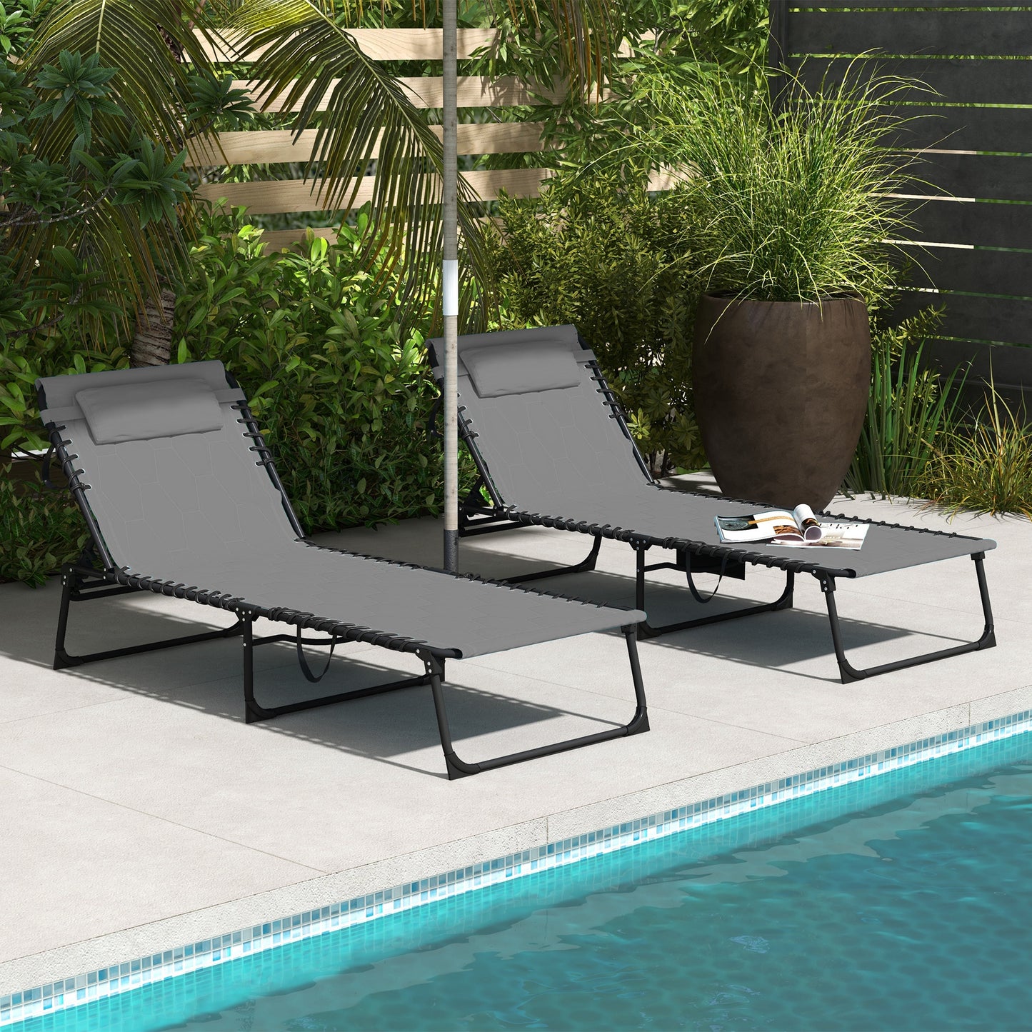 Two grey fabric lounge chairs with black frames sit by a pool