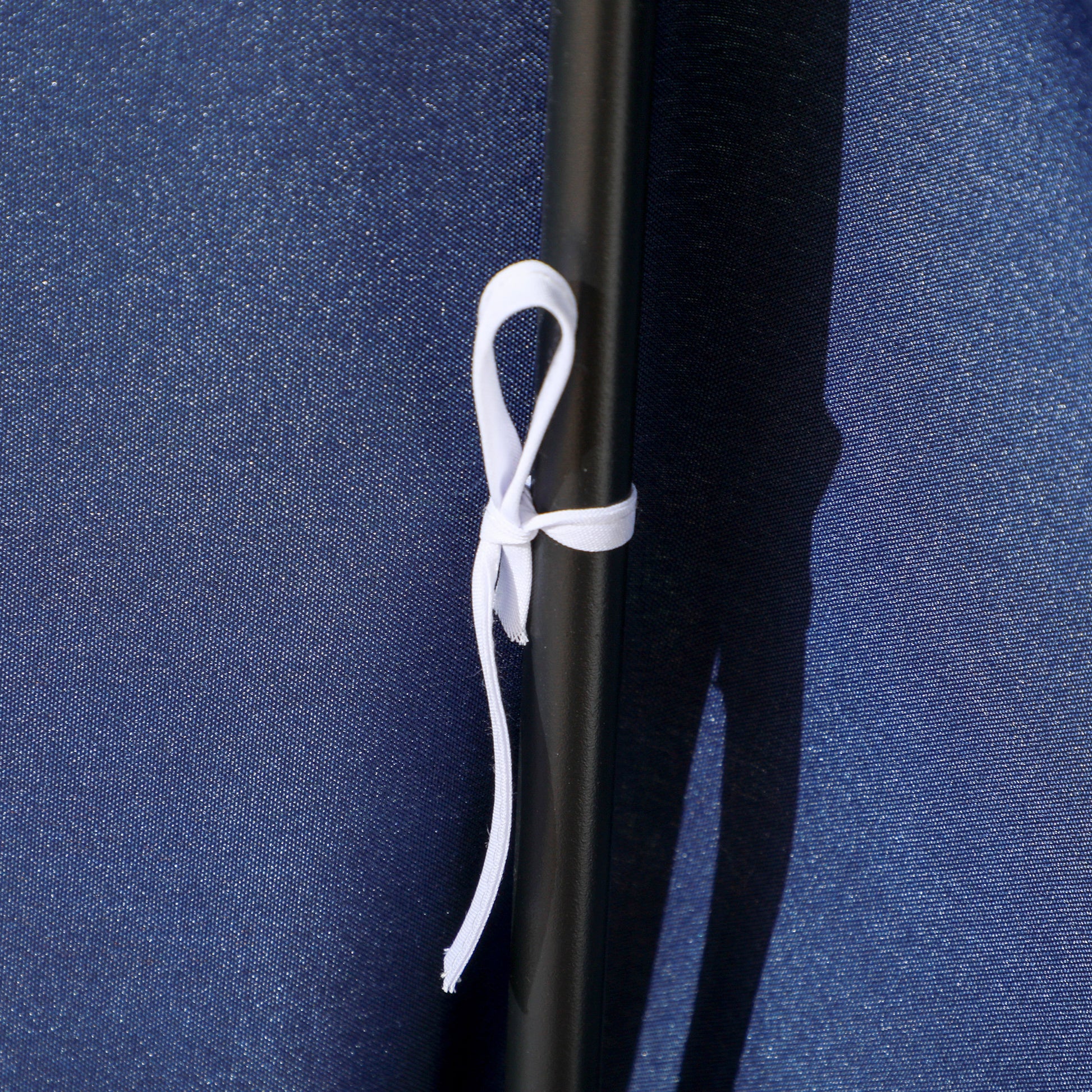 Closeup of dark blue canvas fabric with a black pole and a white tie strap