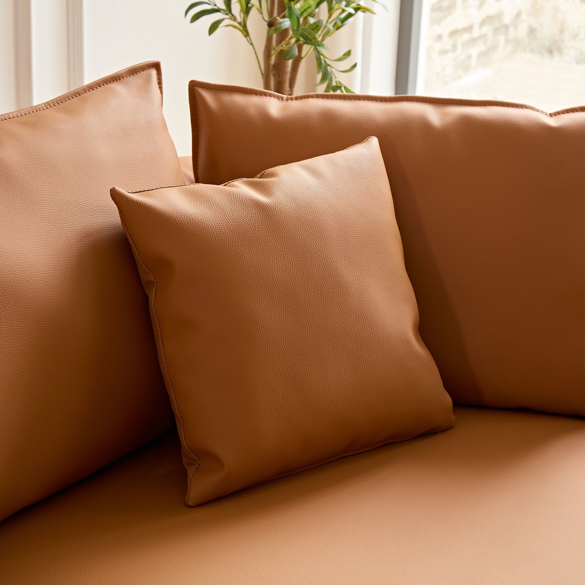 Tan faux leather square throw pillow with stitched edges perfect for living room decor