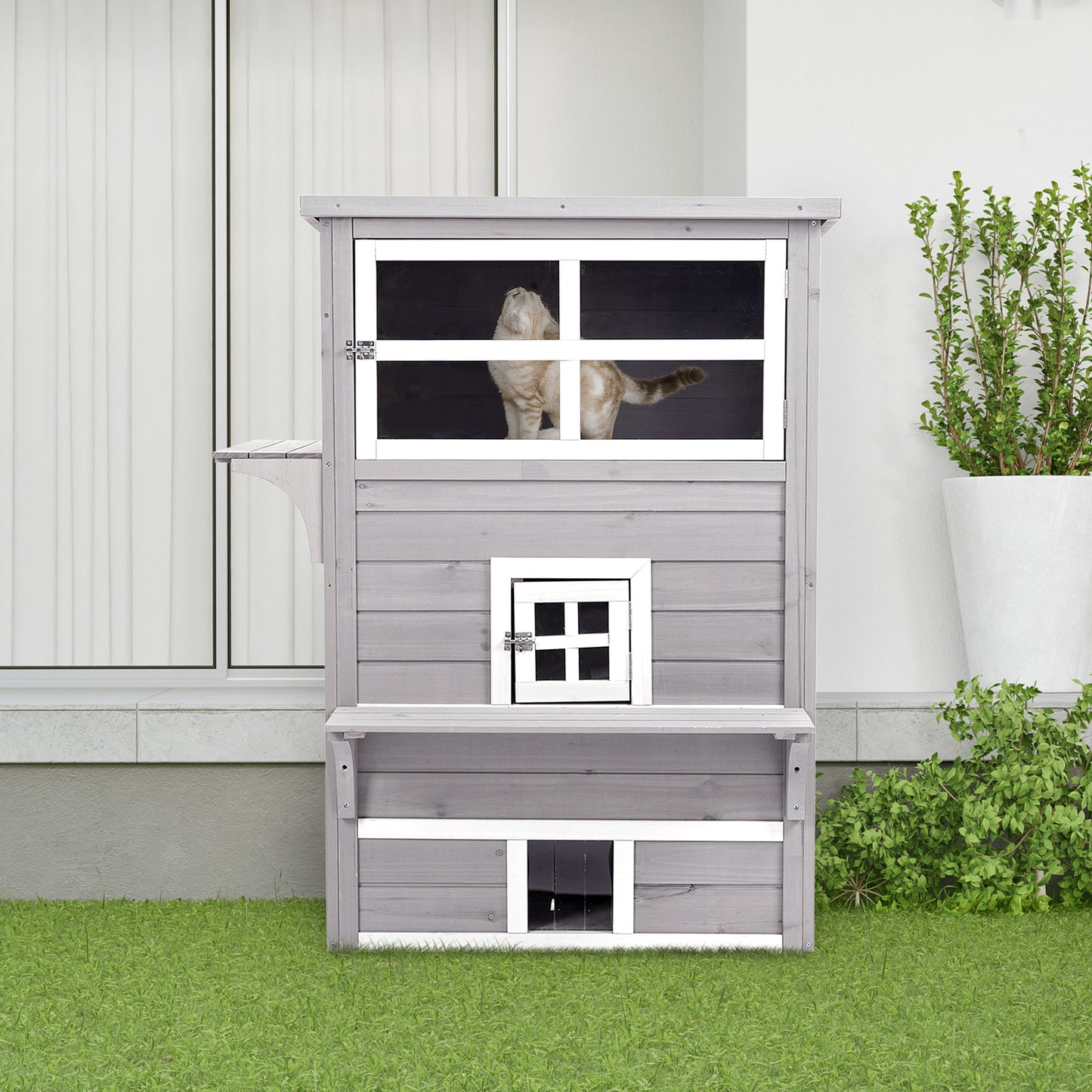 Gray wooden cat condo with multiple levels and windows featuring a cat looking out the top window