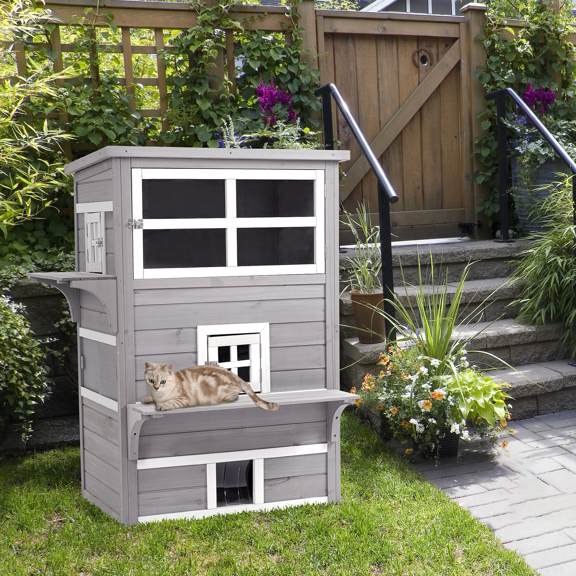 Grey wooden multilevel cat house with windows and a resting cat