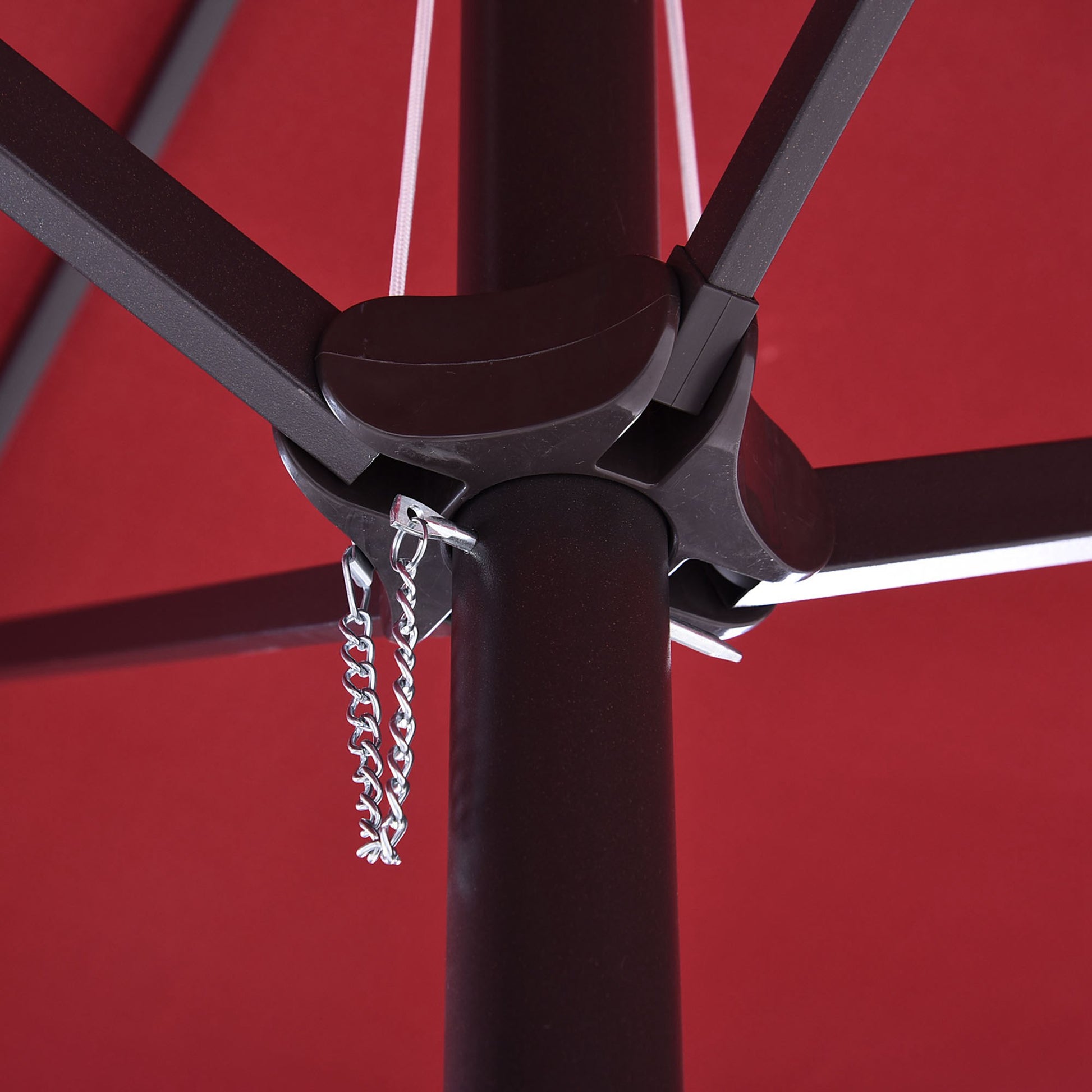 Closeup of red patio umbrella canopy with dark brown pole and silver chain