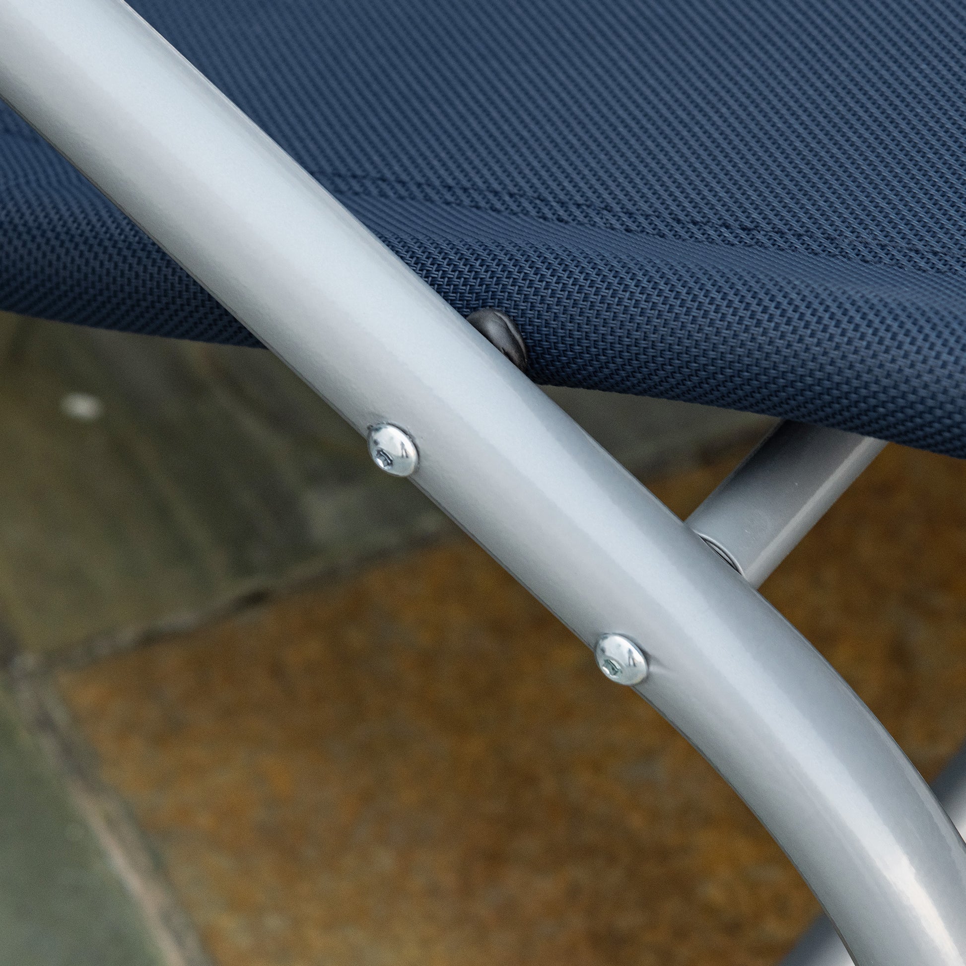 Closeup of a dark blue fabric seat on a silver metal folding chair frame with visible screws