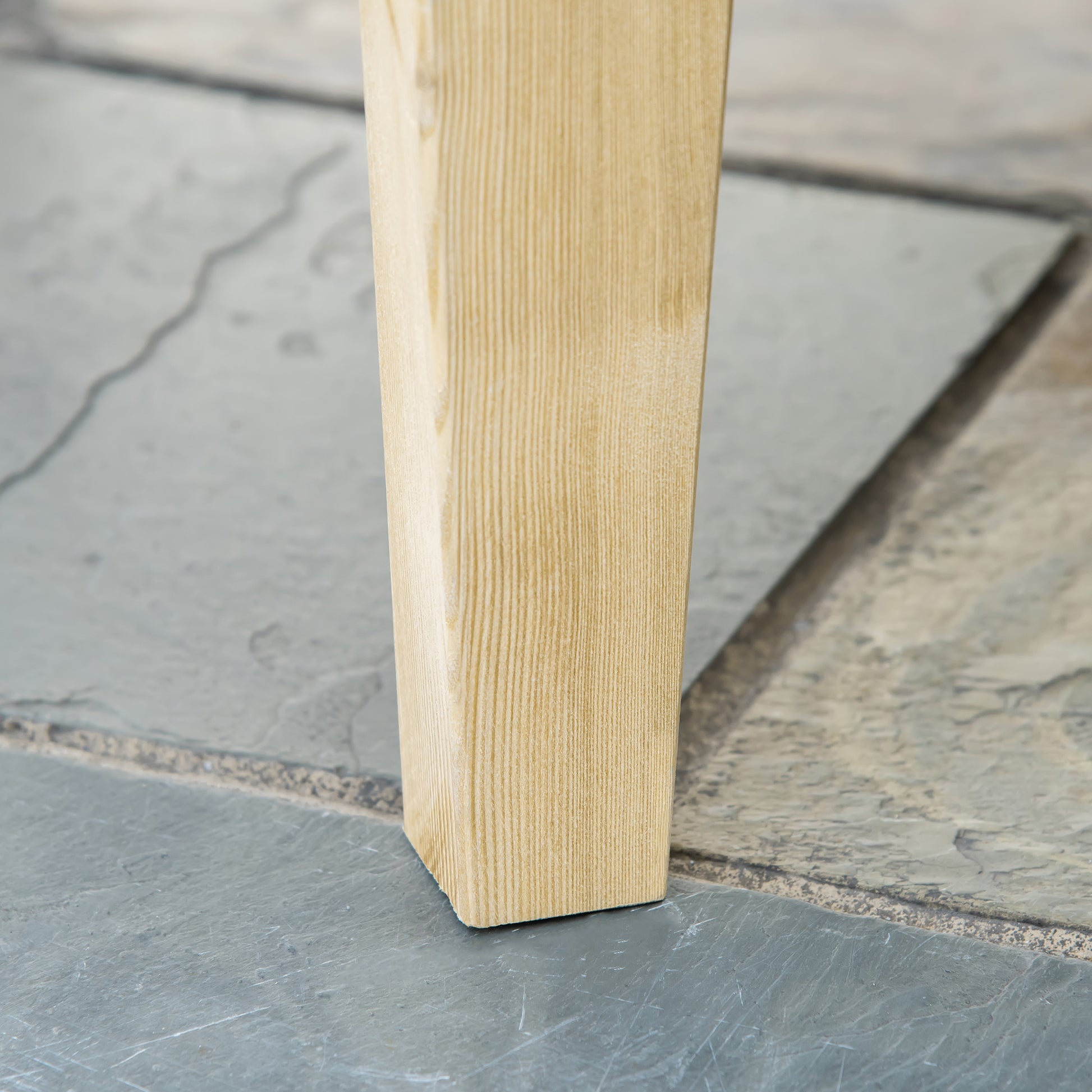 Natural pine wood table leg with visible grain detail on stone flooring