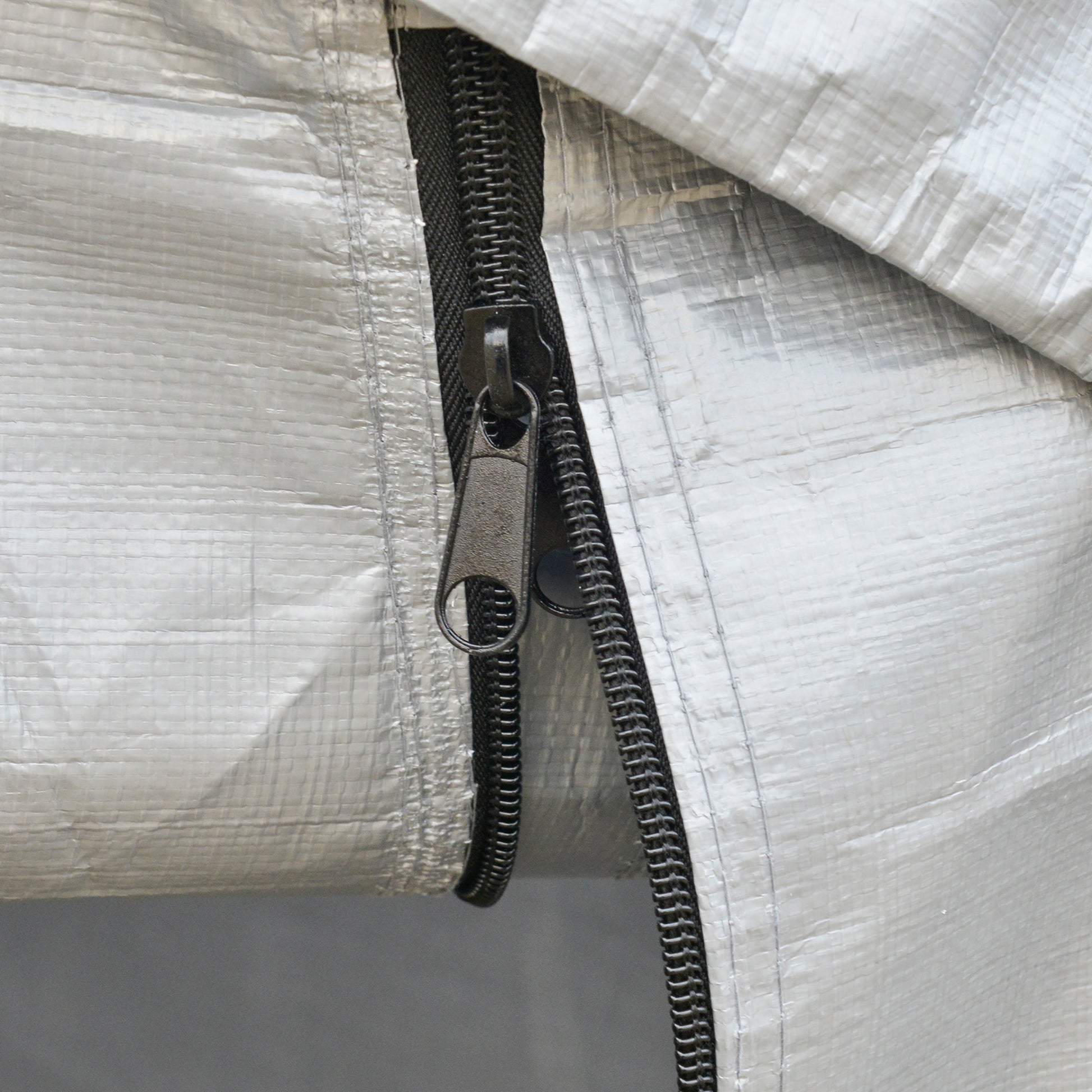 Closeup of a silver polyethylene tarp zipper with a black pull tab for outdoor storage