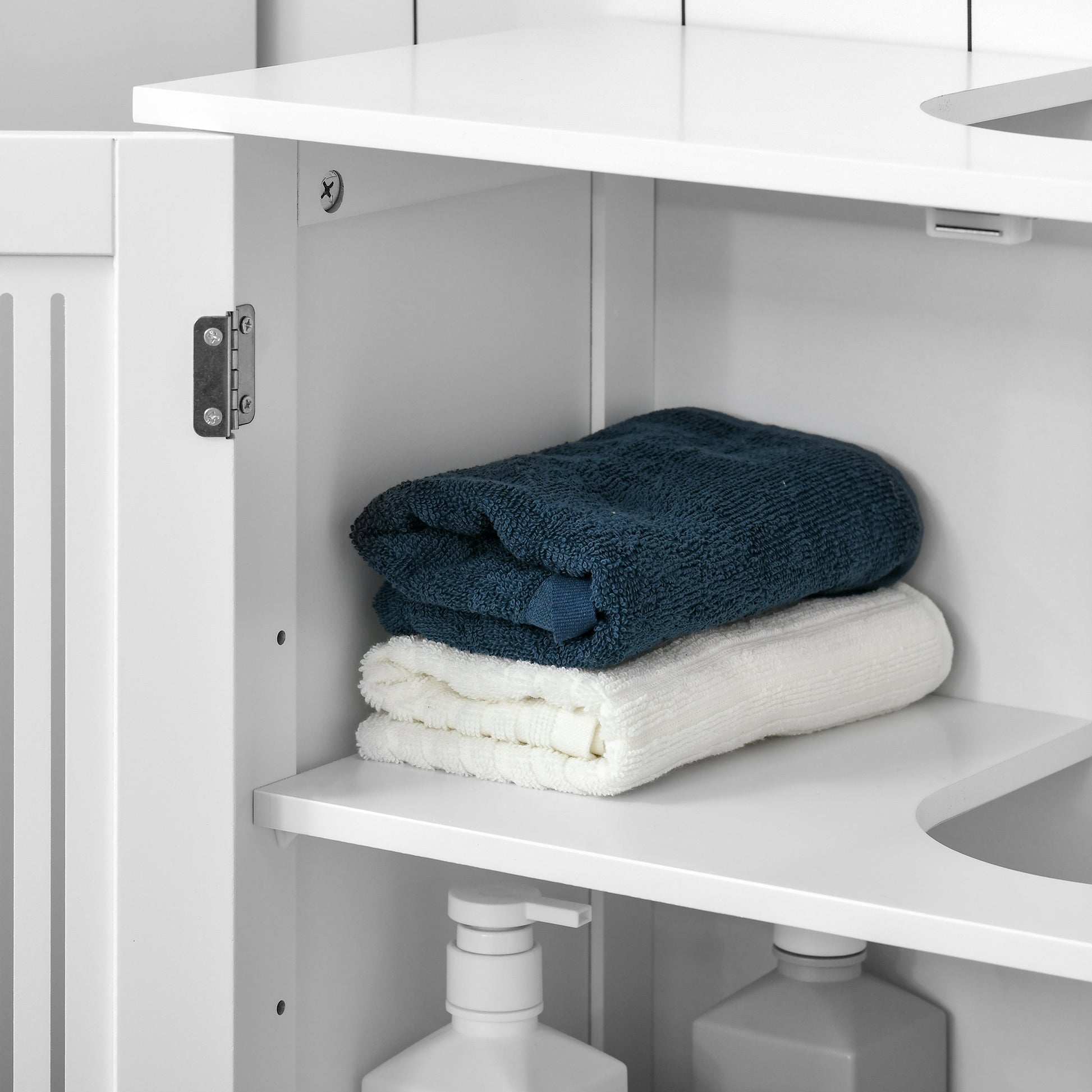 Folded navy blue bath towel stacked on a white towel inside a modern white cabinet