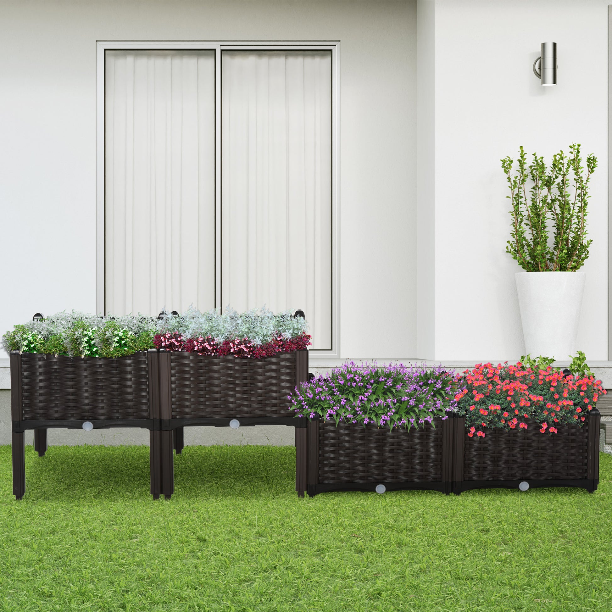Dark brown rattan raised garden bed with wheels overflowing with pink and red flowers