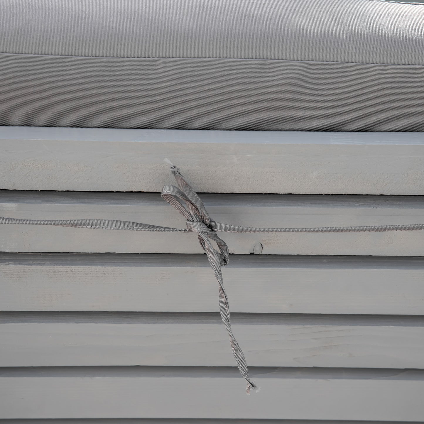 Gray textured outdoor cushion with ties for securing to furniture