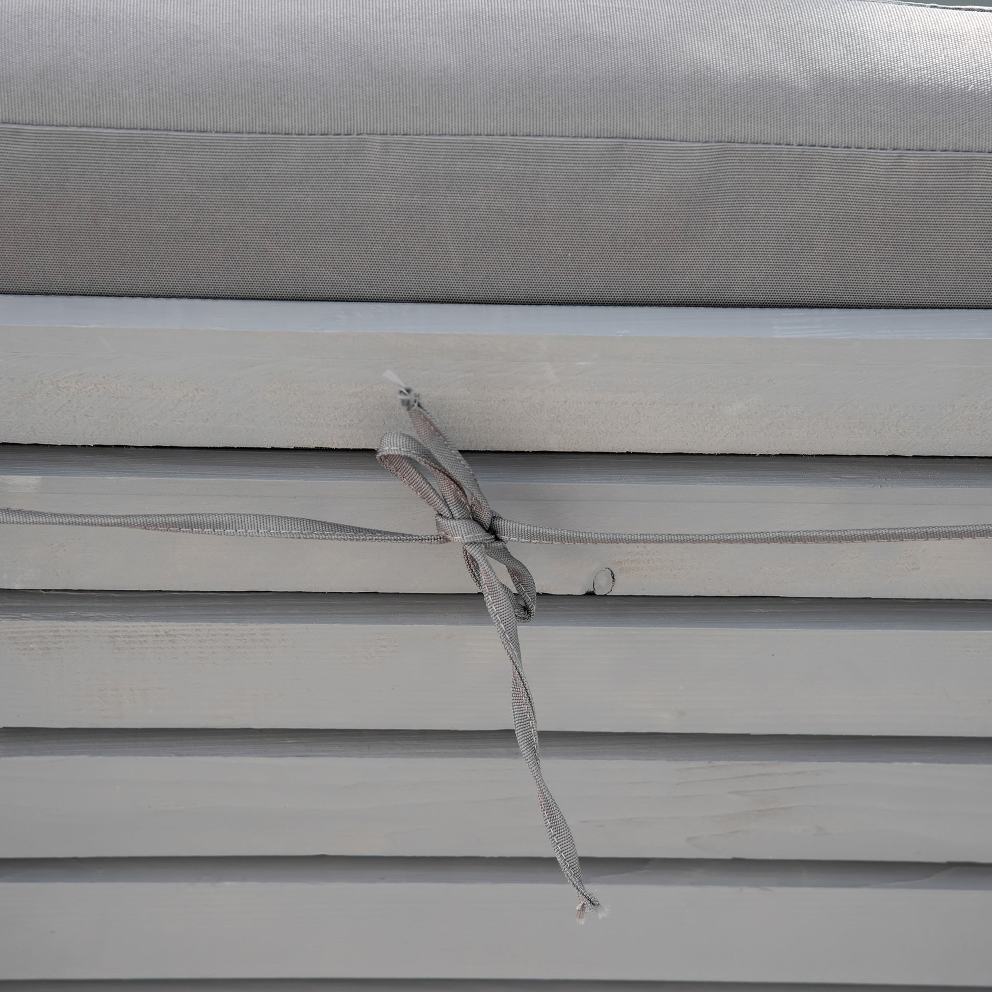 Gray textured outdoor cushion with ties for securing to furniture