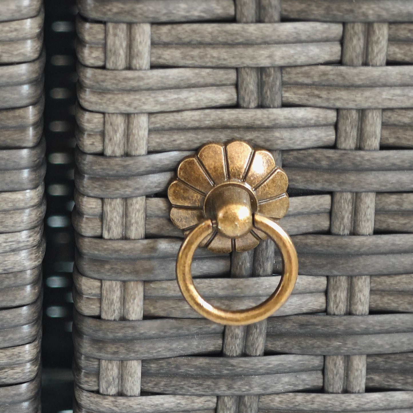 Closeup of grey rattan weave with ornate brass drawer pull