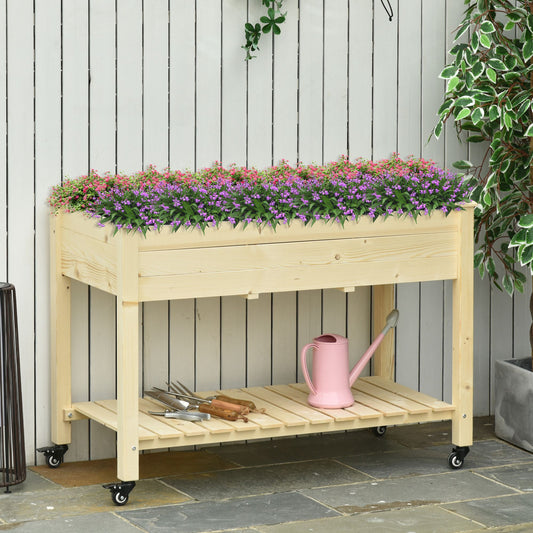 Wooden raised garden bed with pink and purple flowers and gardening tools