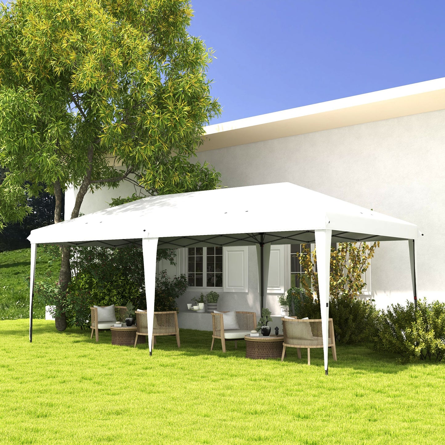 White popup canopy tent with wicker chairs and table in lush green backyard
