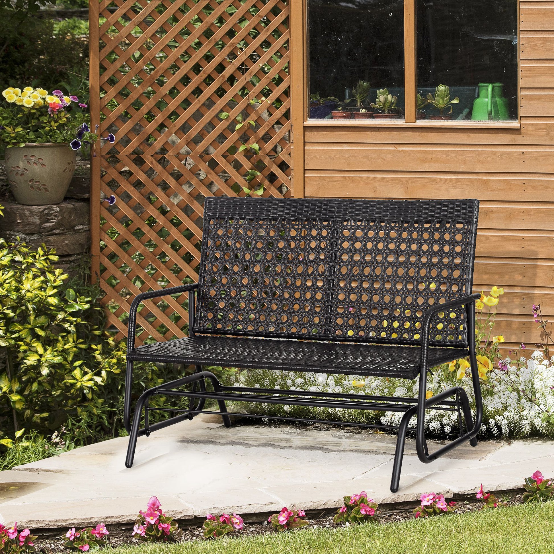 Black rattan garden bench with curved metal frame set on a patio