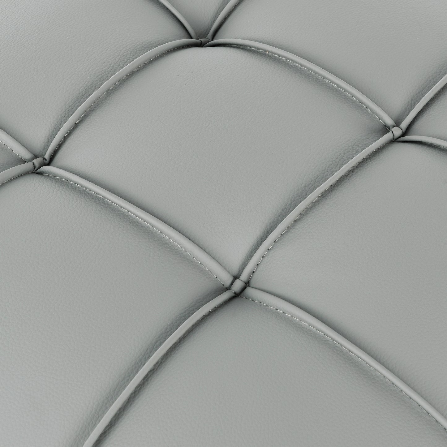 Closeup of grey faux leather upholstery with diamond tufting showcasing material texture