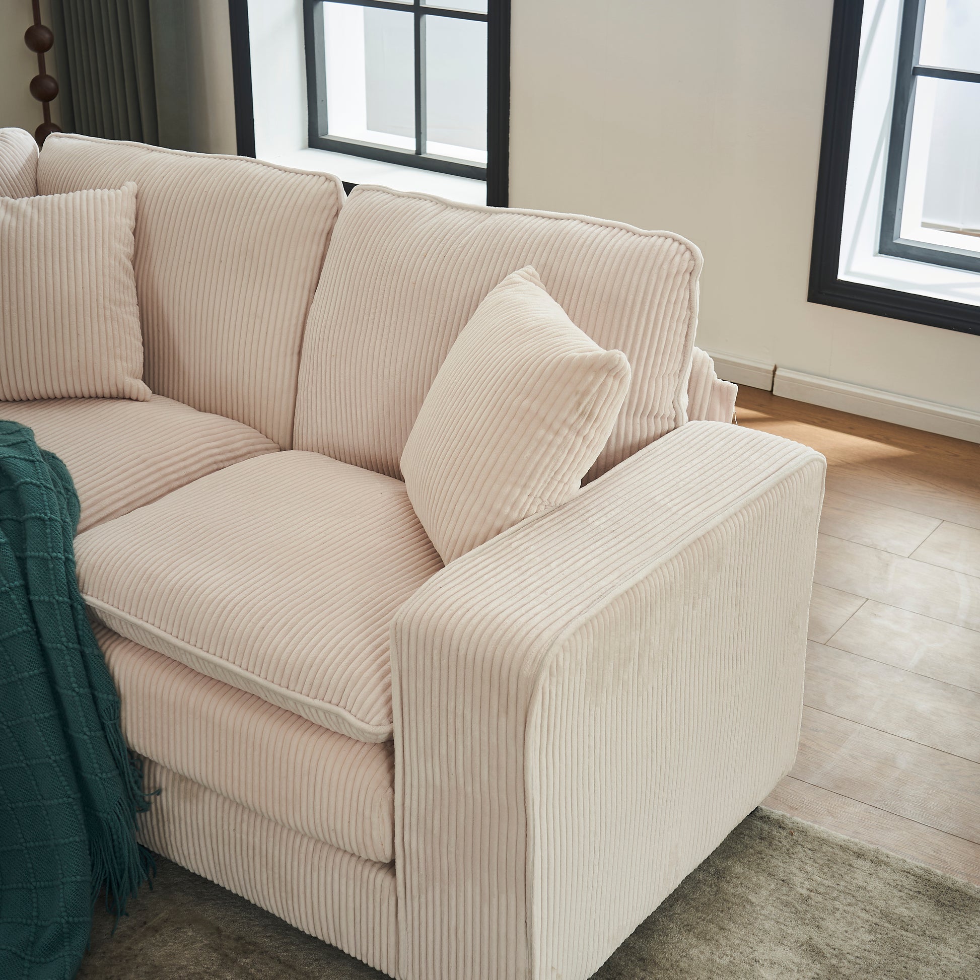 Soft blush corduroy sofa with plush cushions and a teal throw blanket