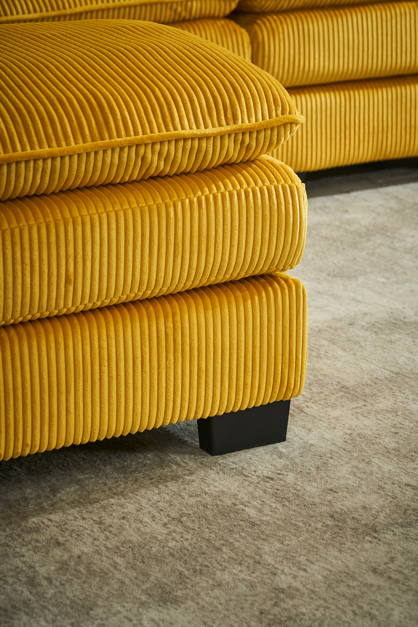 Yellow corduroy sofa section with plush cushions and black legs
