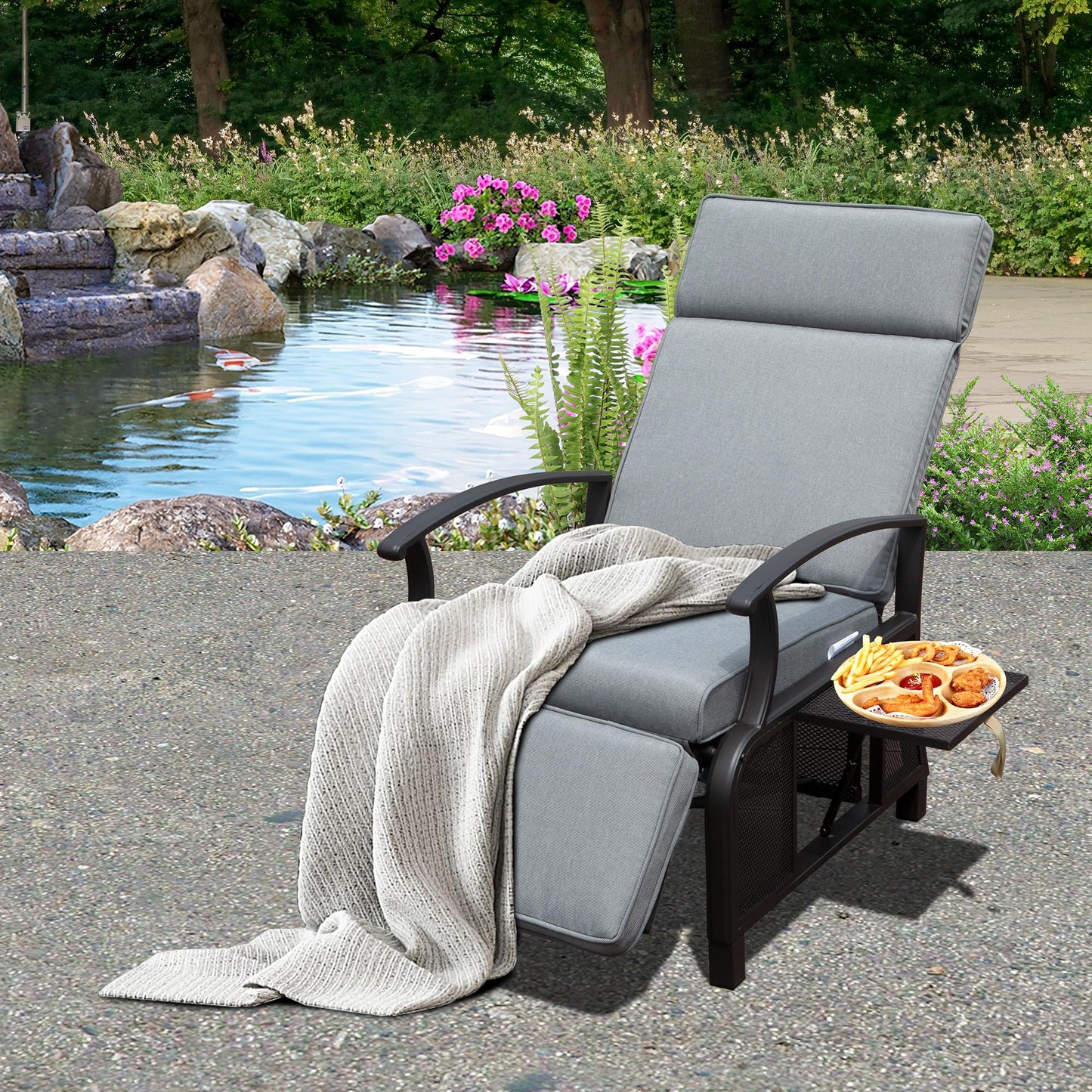 Gray outdoor reclining lounge chair with plush cushions and a side tray holding fried snacks