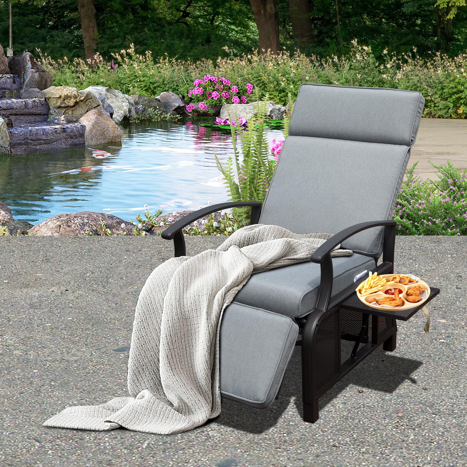Gray outdoor reclining lounge chair with plush cushions and a side tray holding fried snacks