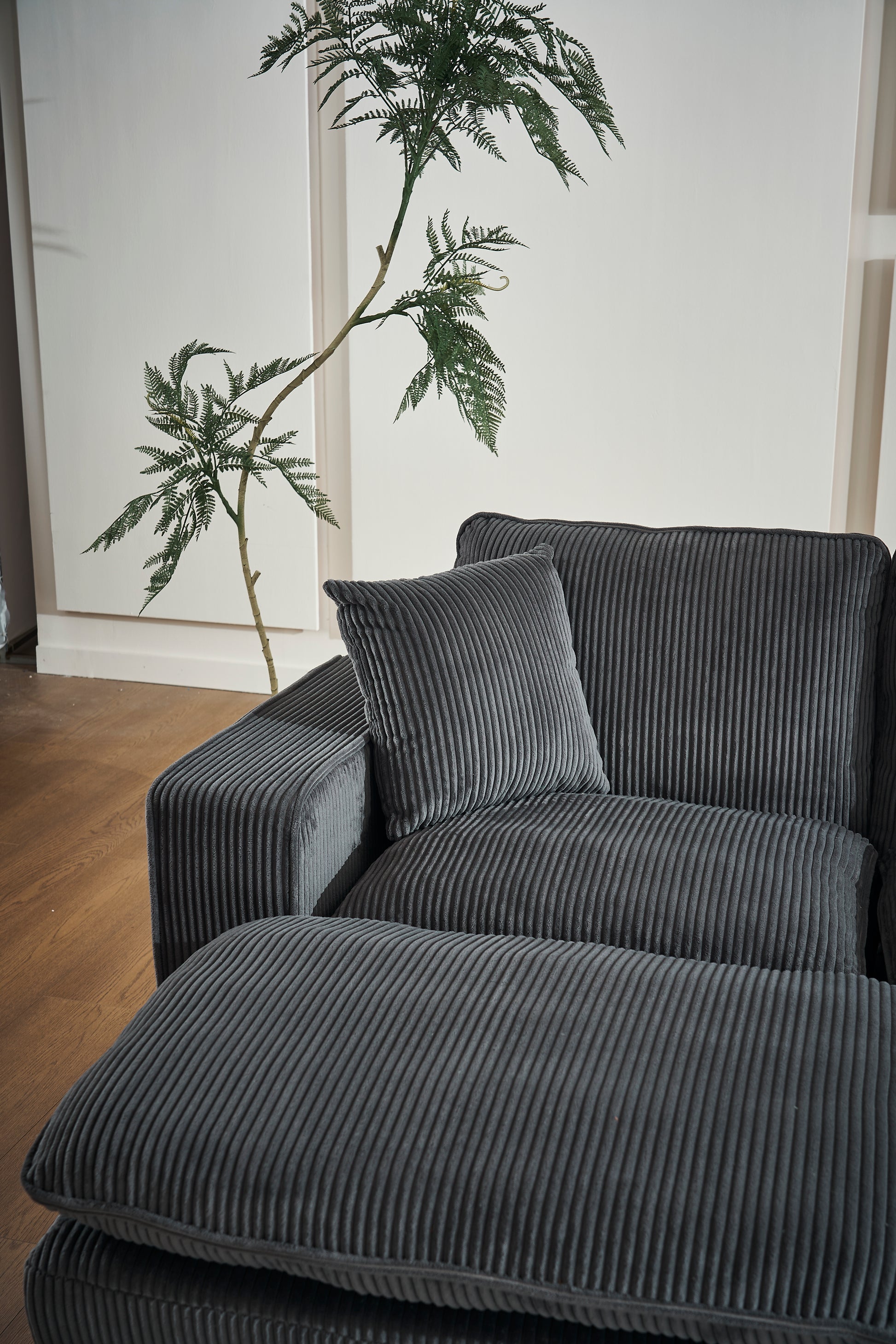 Dark grey corduroy sectional sofa with plush cushions and an ottoman perfect for modern living rooms