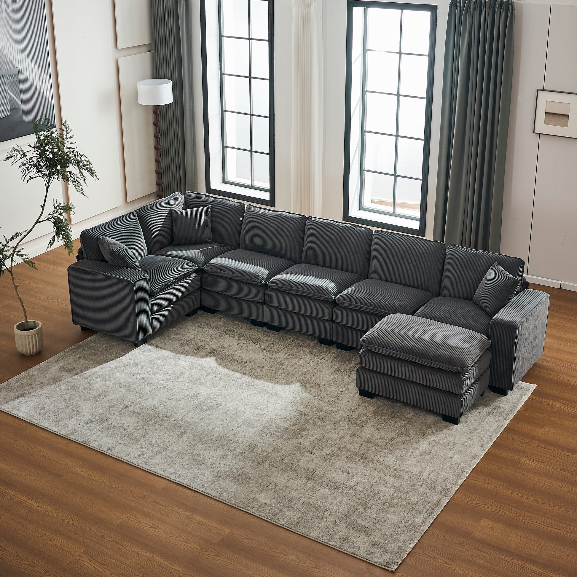 Dark gray corduroy sectional sofa with plush cushions and an ottoman ideal for modern living rooms