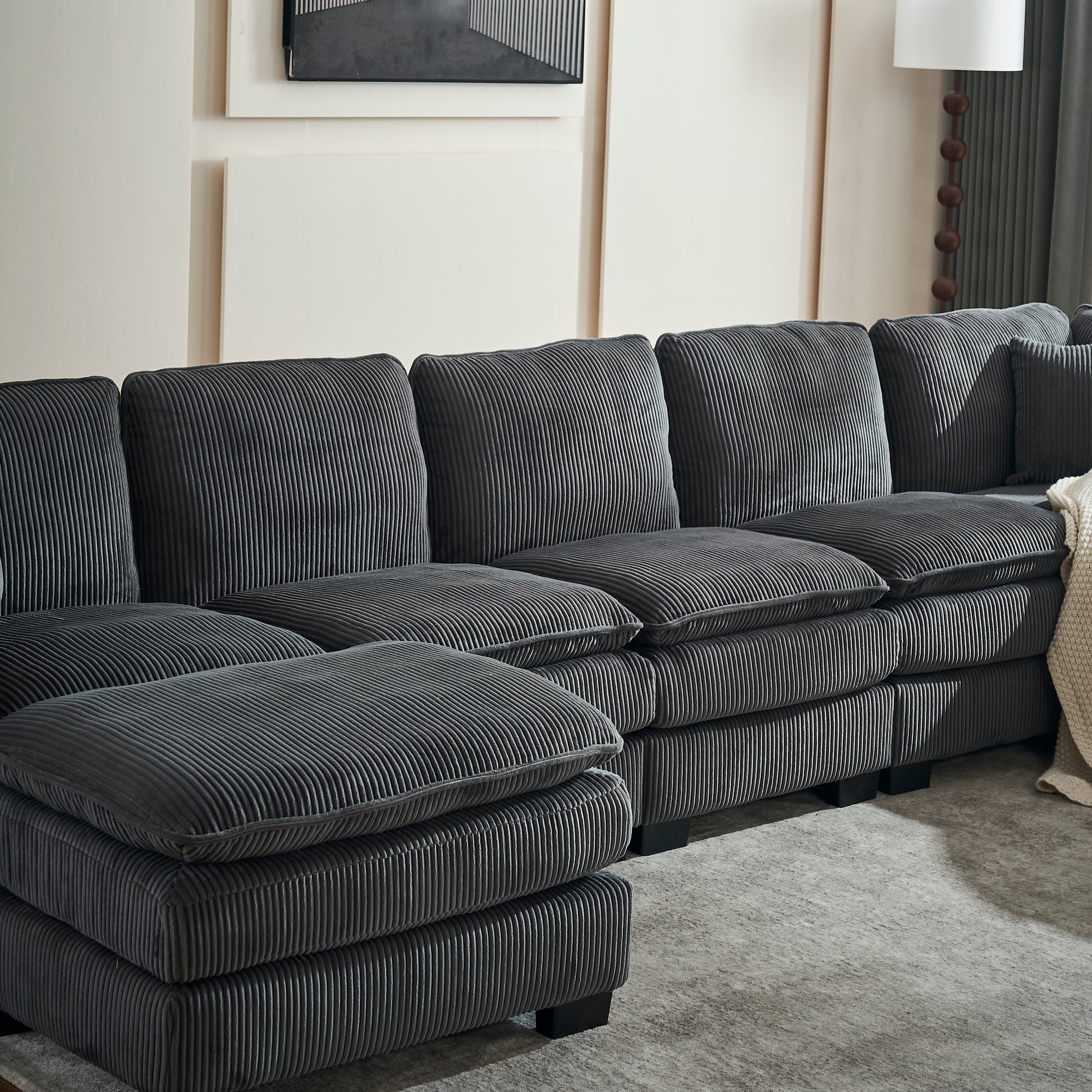 Sectional sofa in dark grey corduroy fabric with plush cushions and matching ottoman perfect for modern living rooms