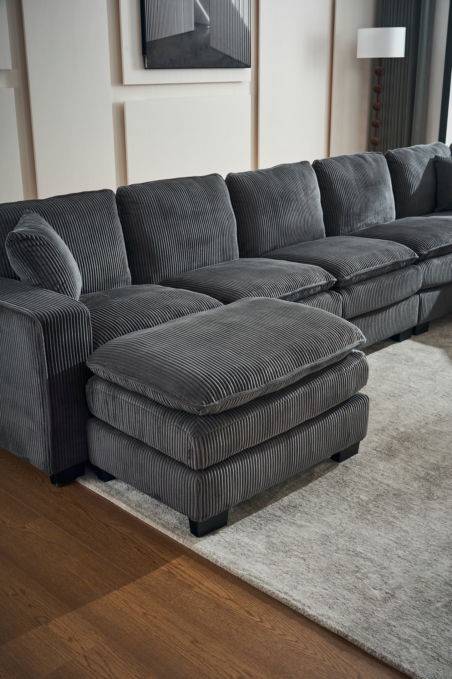 Deep charcoal corduroy sectional sofa with plush cushions and a matching ottoman perfect for modern living rooms