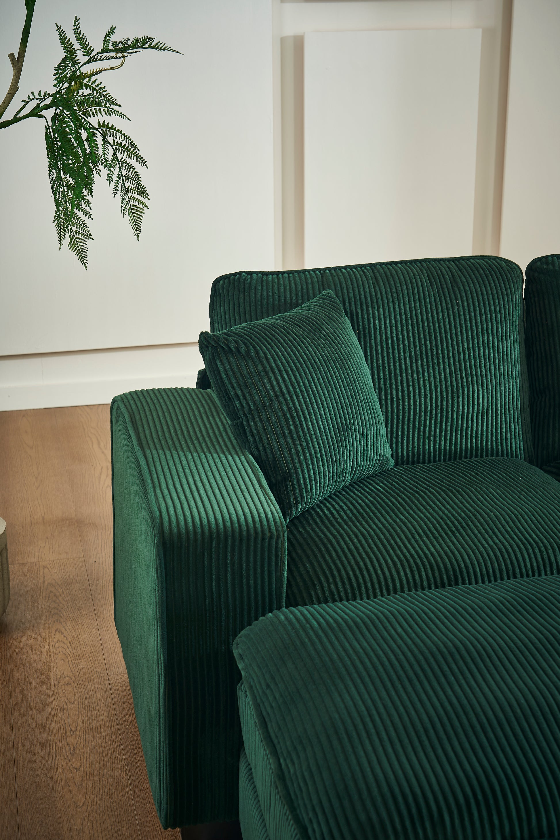 Plush dark green corduroy sofa with a matching throw pillow for a cozy living room