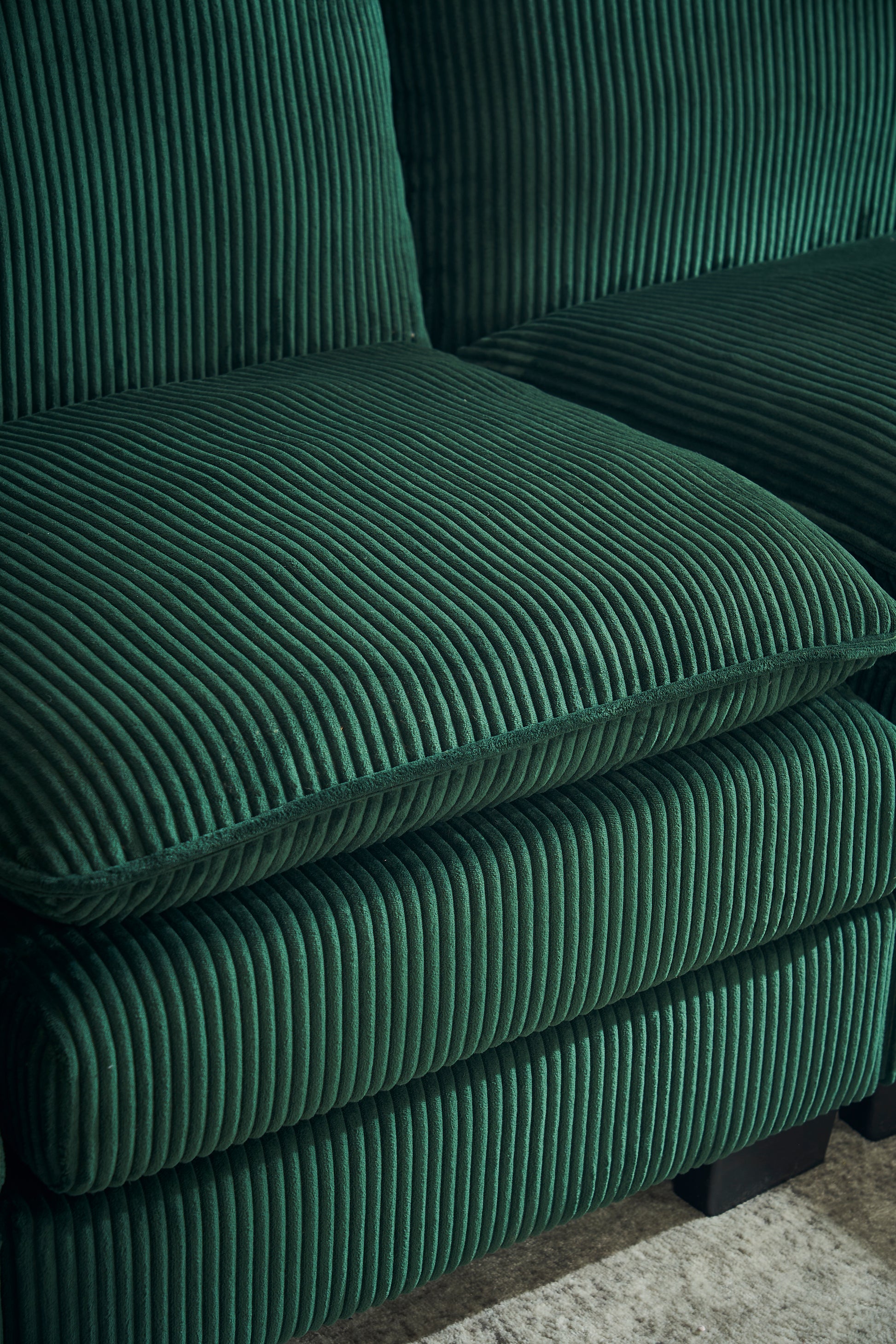 Deep emerald green corduroy sofa cushions with vertical ribbing texture
