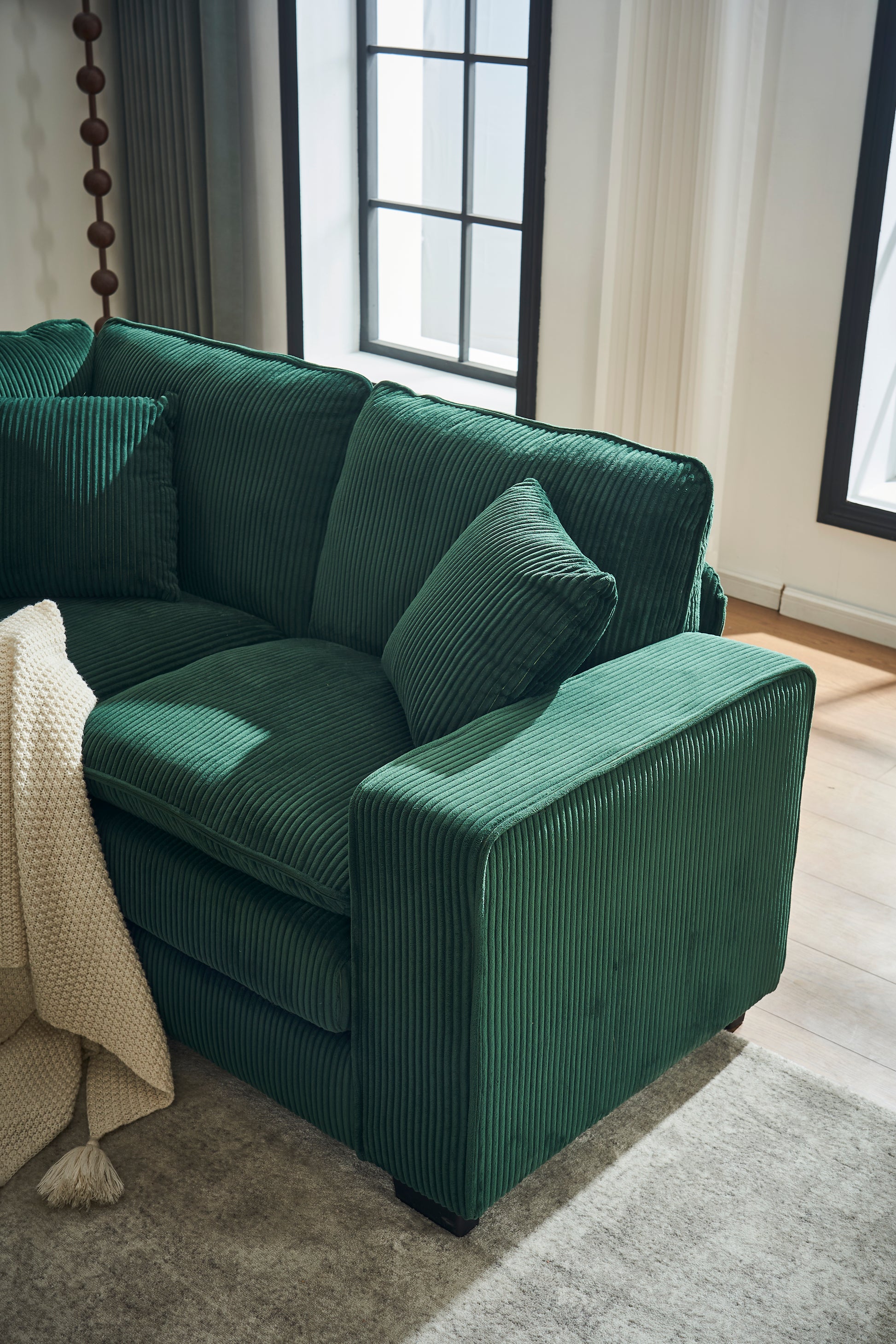 Deep green corduroy sectional sofa with plush cushions and accent pillows