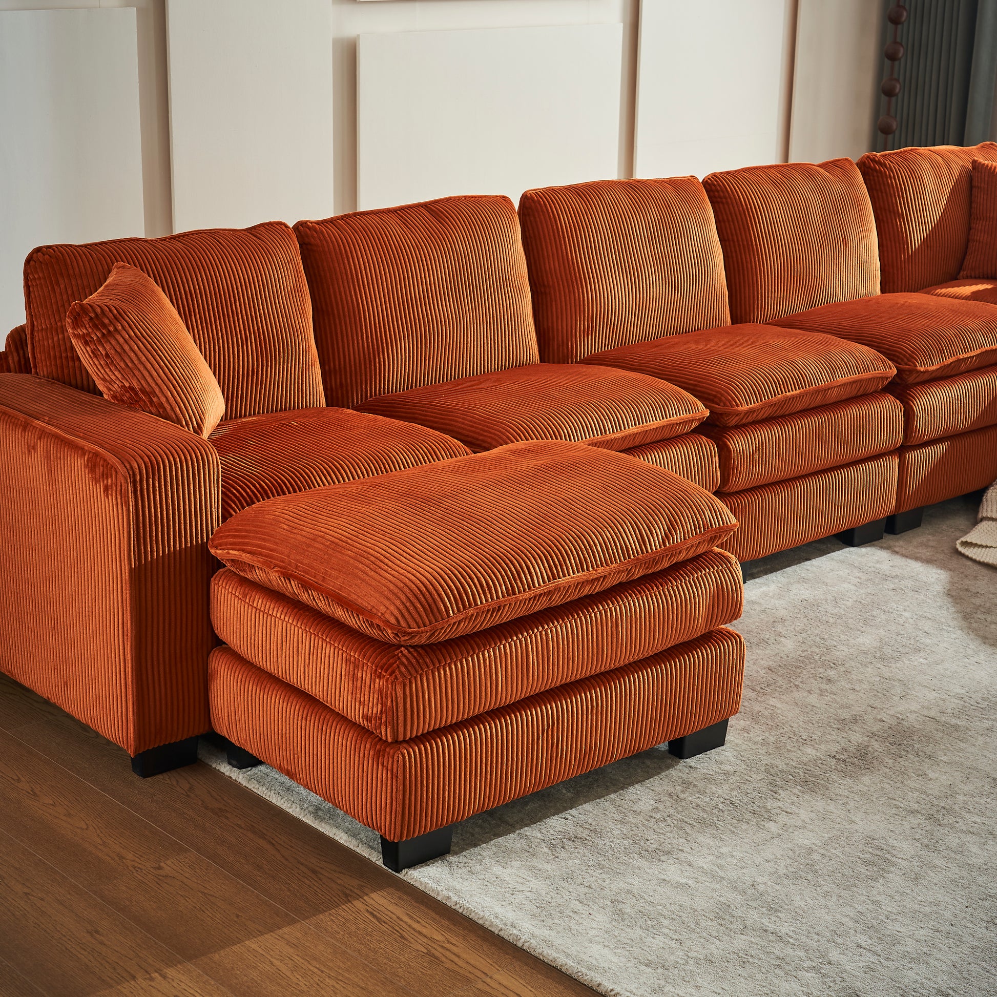 Orange corduroy sectional sofa with plush cushions and an ottoman