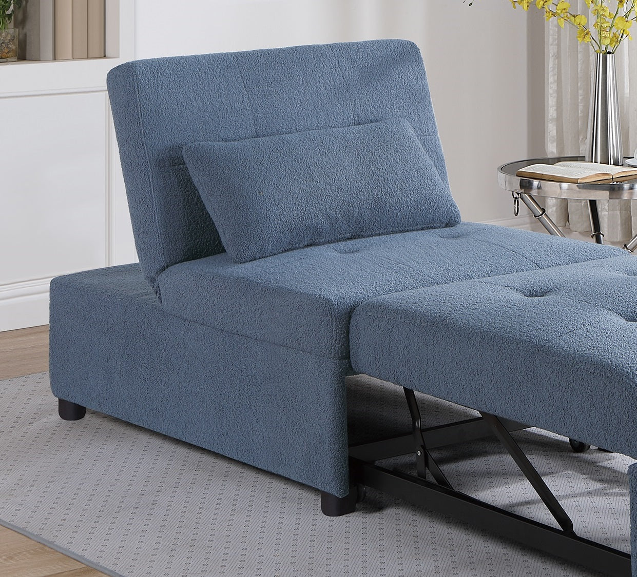 Blue fabric convertible sleeper chair with matching pillow and ottoman on grey rug