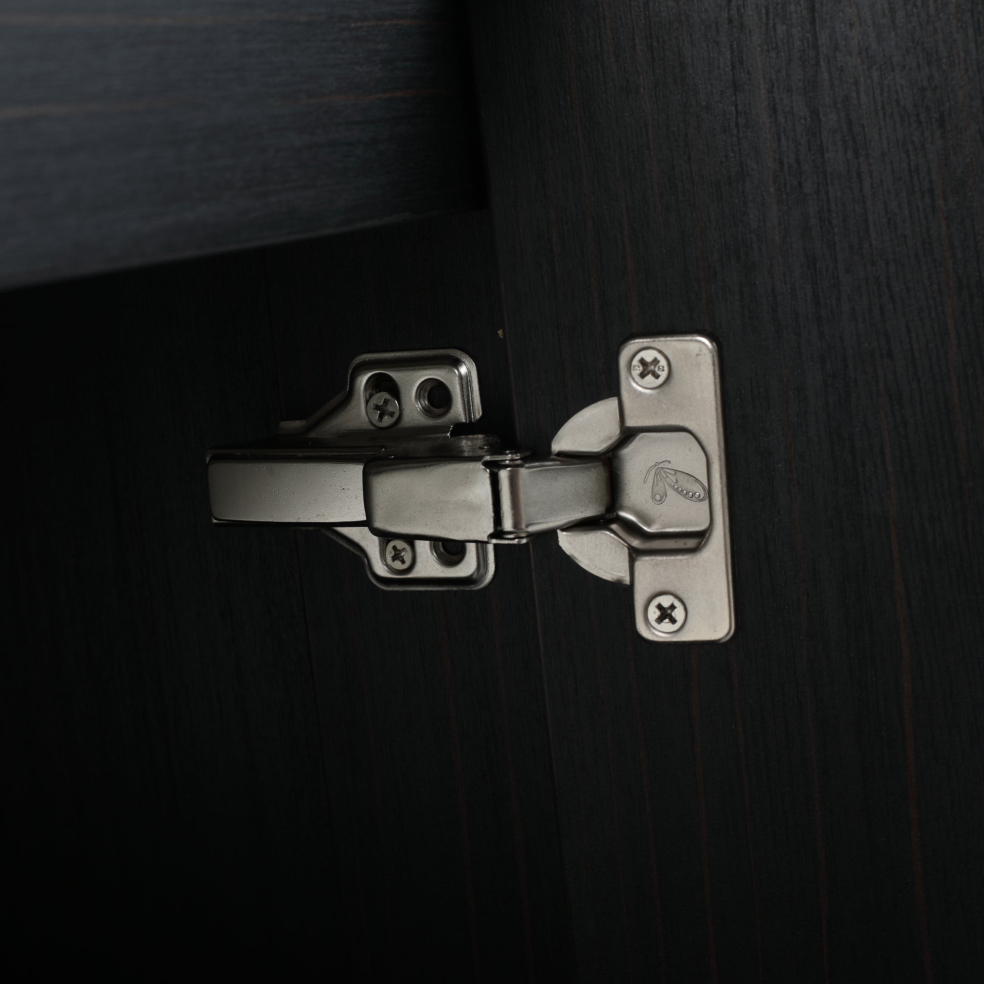 Silver cabinet hinge with butterfly design featuring precise screw attachments on dark wood